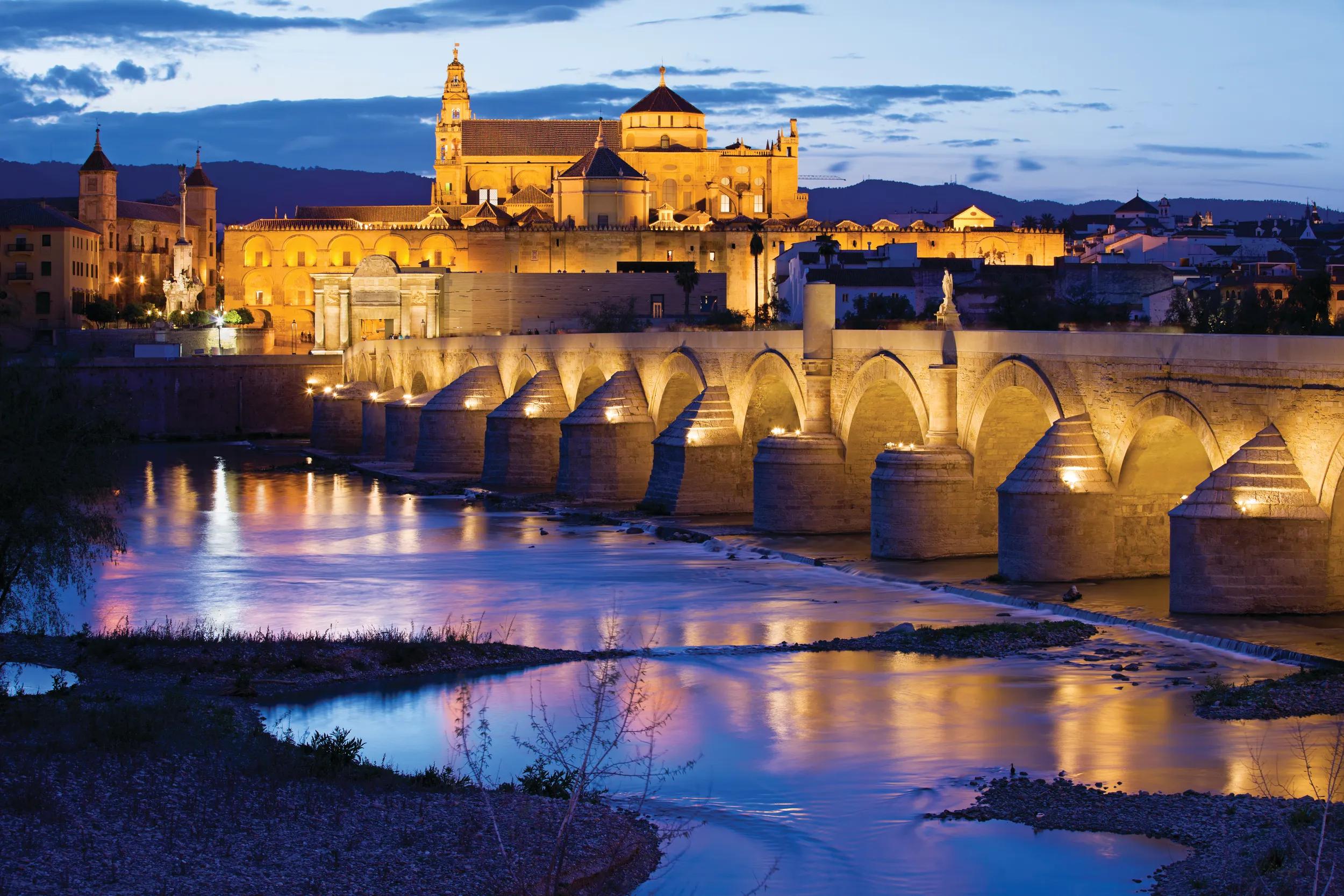 Roman Bridge on Guadalquivir river and Mezquita Cathedral (Great Mosque) at twilight in city of Cordoba, Andalusia, Spain.
