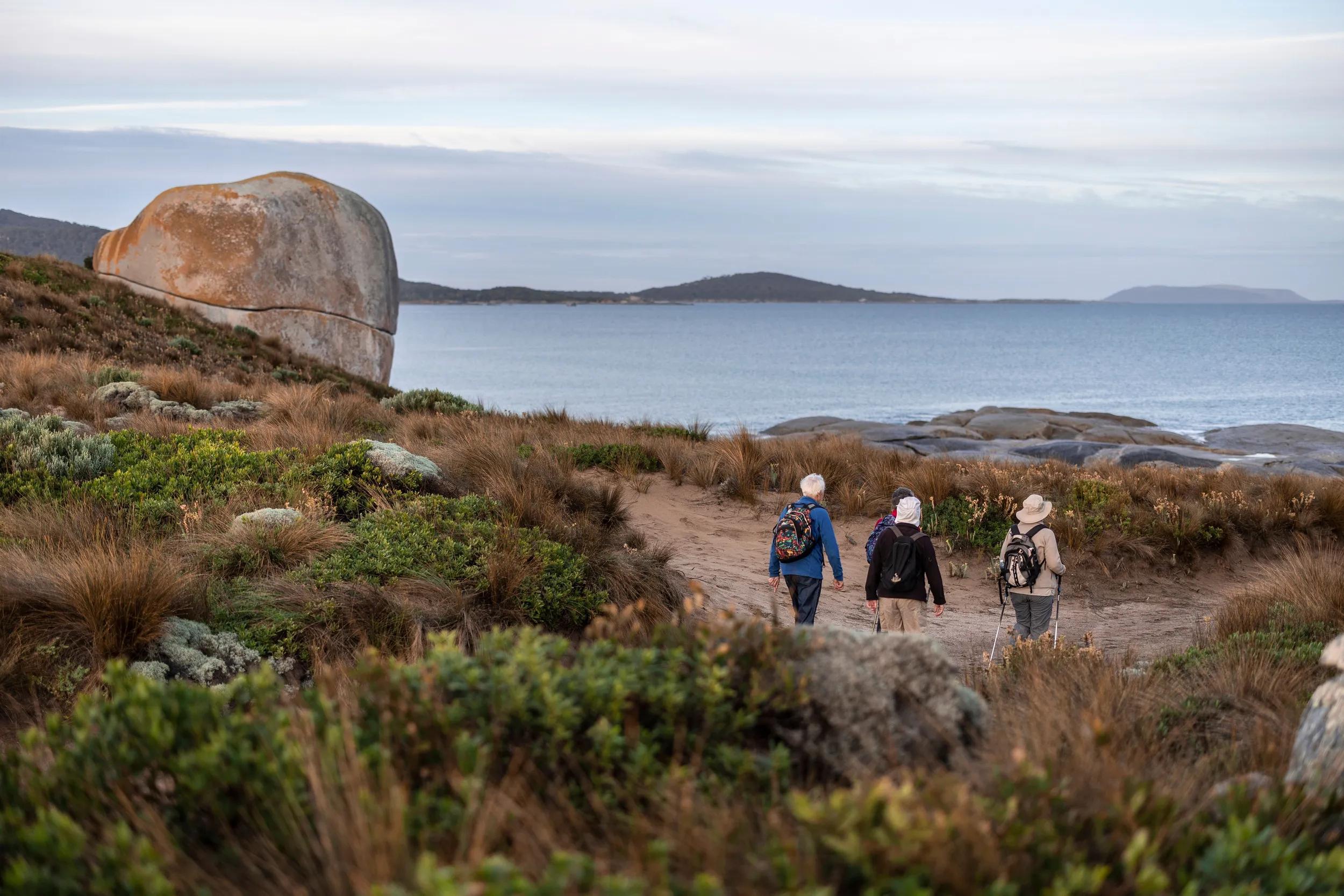 People hiking in Marshall Bay, near Castle Rock, Flinders Island, Tasmania.