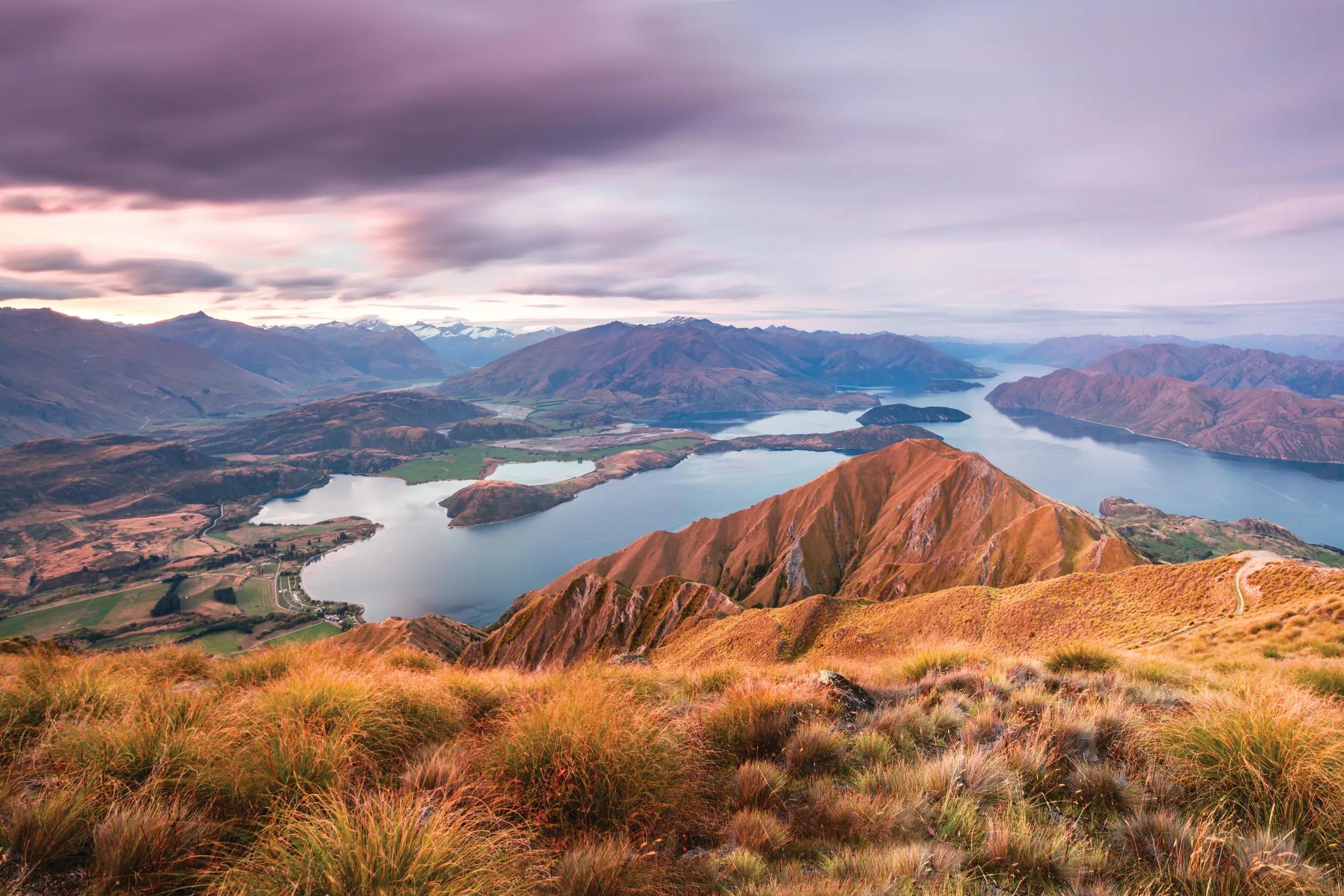 Sunset over Wanaka lake and Southern Alps mountain range with Mt Aspiring visible, from Mt Roy. Wanaka, Otago region, New Zealand.