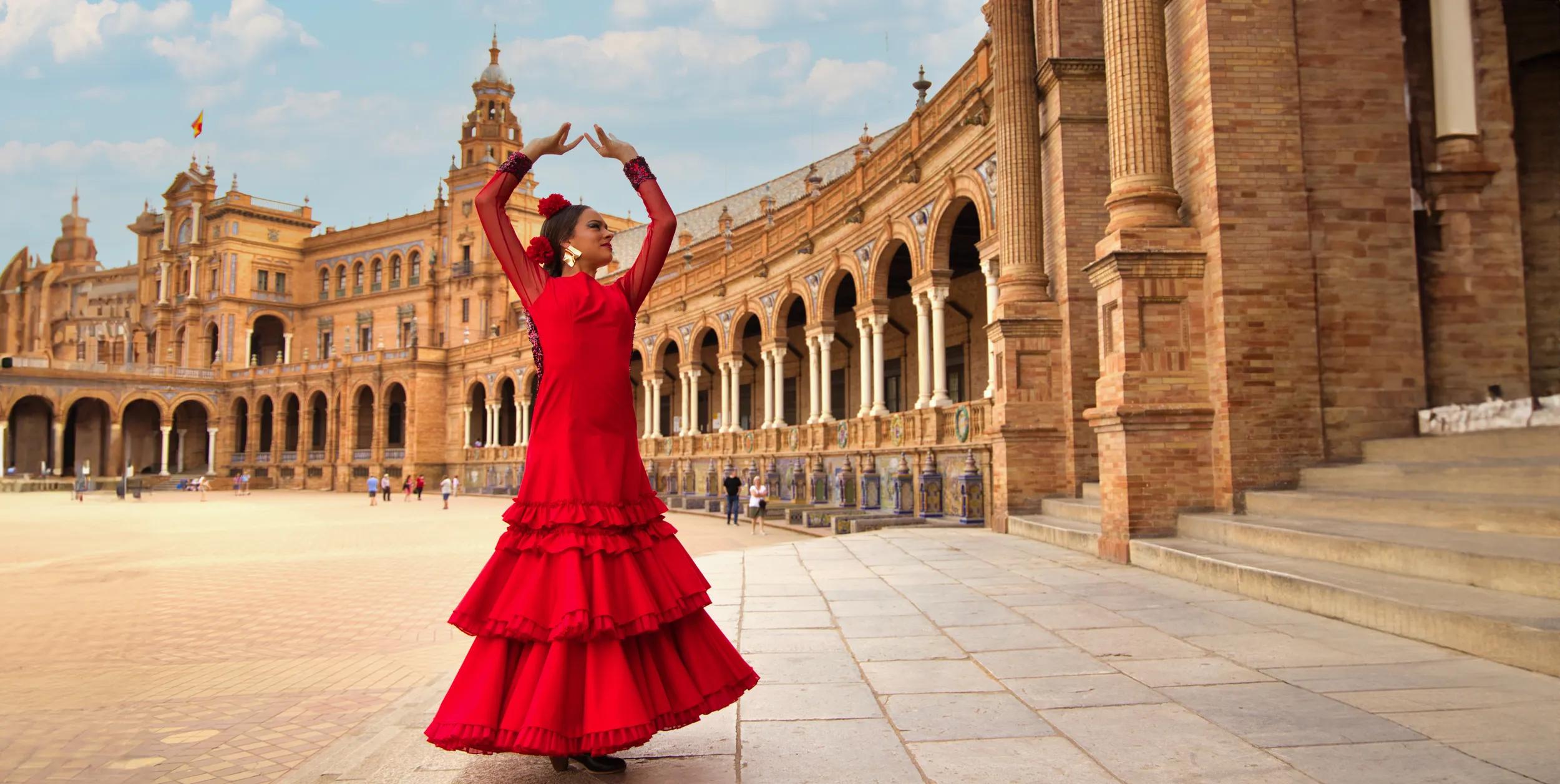 Beautiful teenage woman in traditional red flowing dress, dancing flamenco in a square in Seville, Spain. 