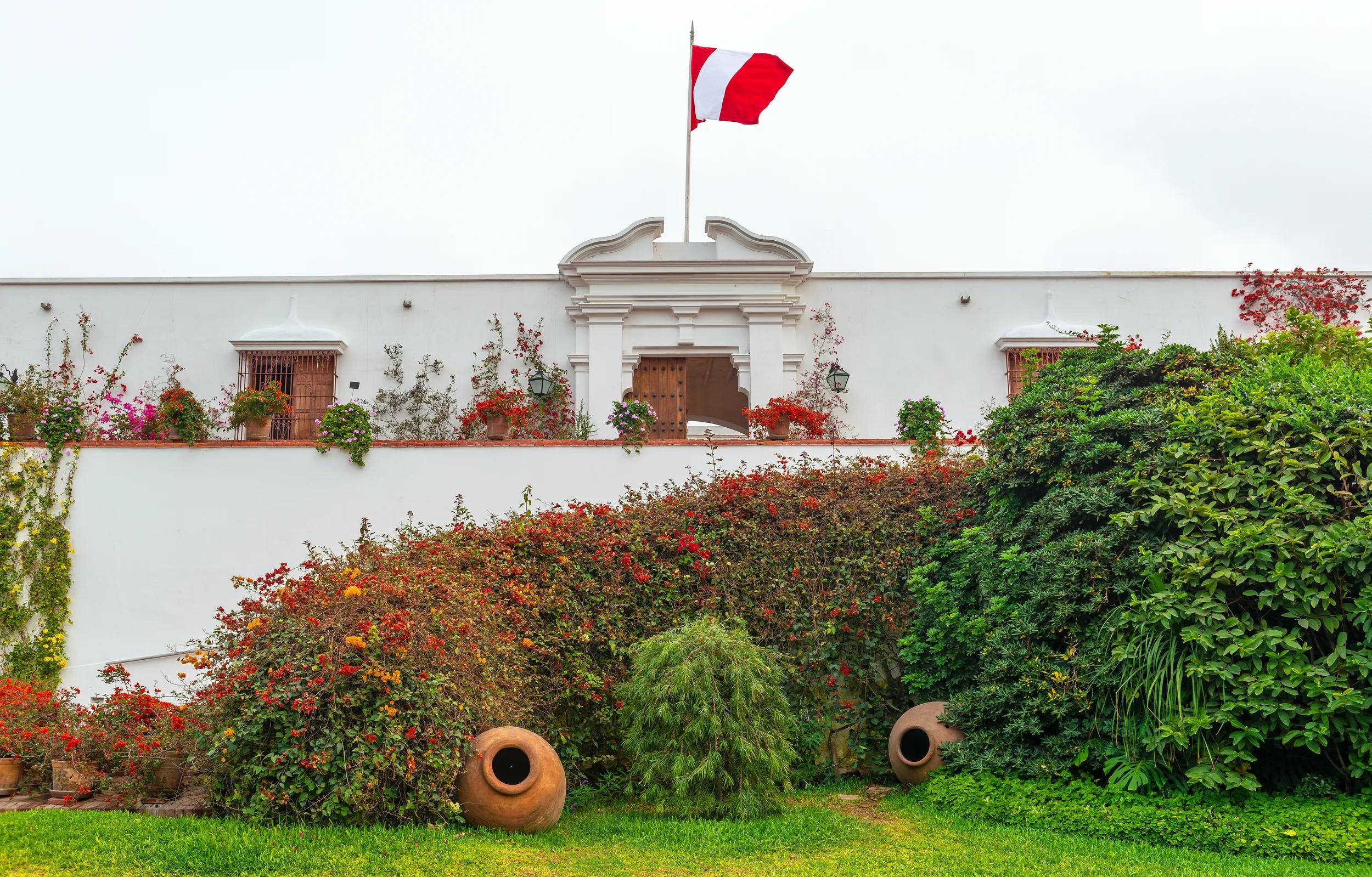 Entrance facade and door of the archaeology museum Larco Herrera with garden and peruvian flag, Lima, Peru.