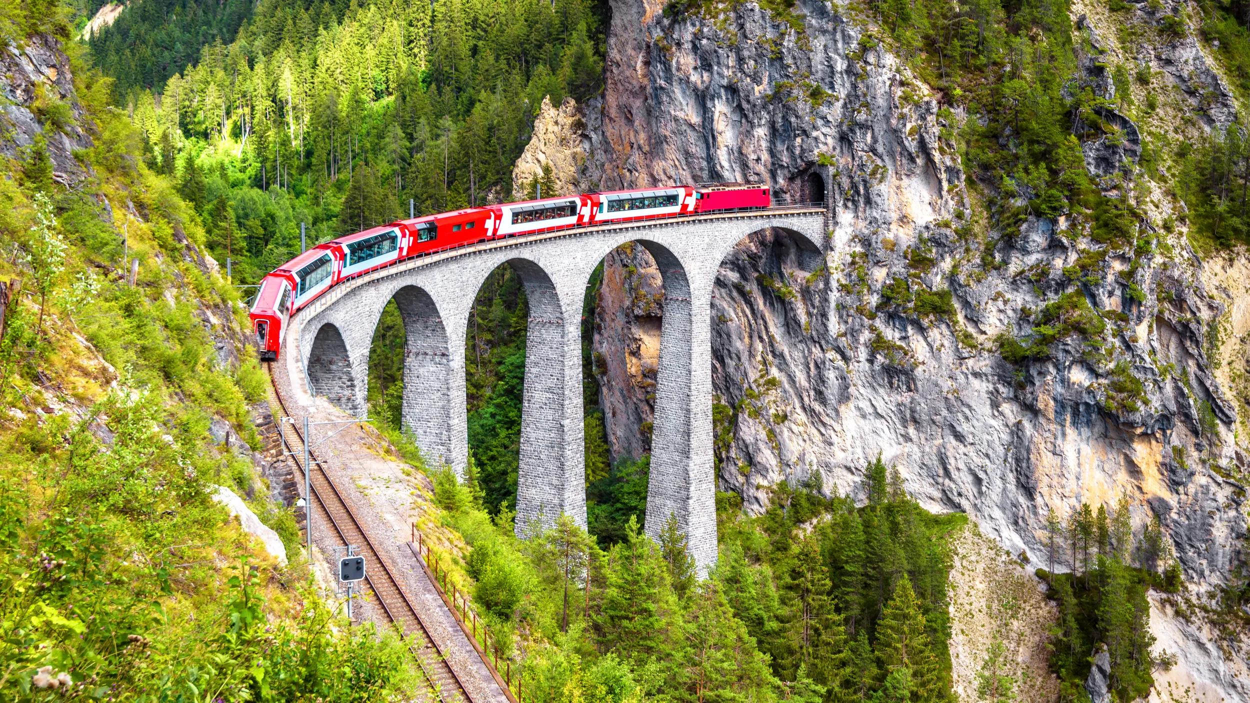 Landwasser Viaduct in summer, Filisur, Switzerland. It is landmark of Swiss Alps. Nice Alpine landscape. Red train of Bernina Express on railroad bridge in mountains. Scenic view of famous railway.