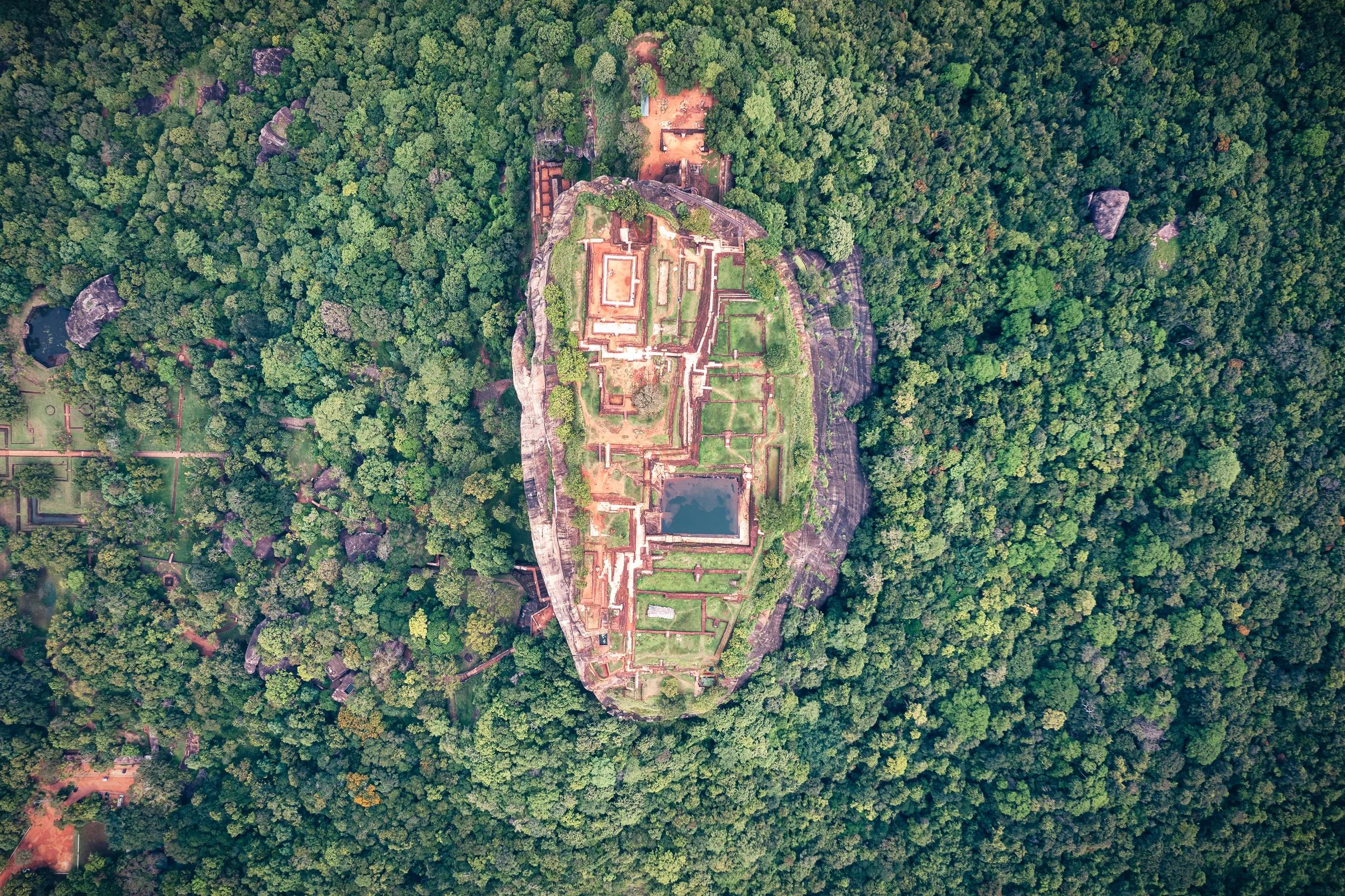Top down view of the magnificent Sigiriya Lion's Rock, in Sri Lanka. The drone is above the clouds...Sigiriya is an ancient rock fortress located in the northern Matale District near the town of Dambulla in the Central Province, Sri Lanka. ..It is a site of historical and archaeological significance that is dominated by a massive column of rock 180m high...Photo taken by drone device.