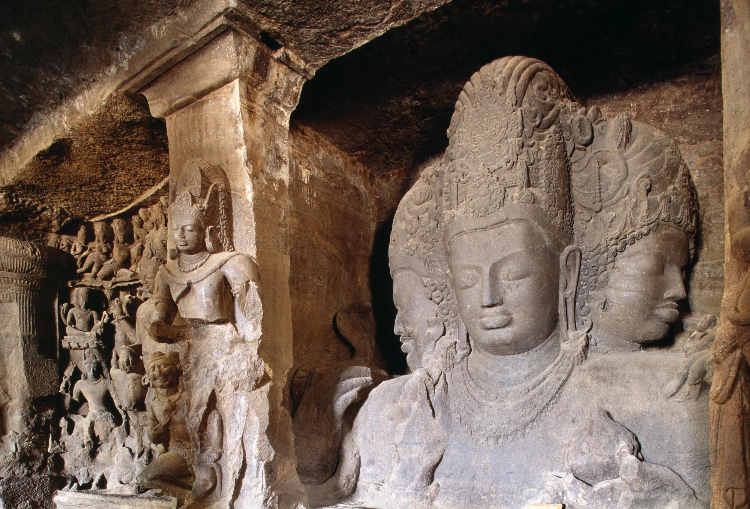 Sculpture of a triple-headed Shiva with a guardian in the main hall of the Elephanta Caves.