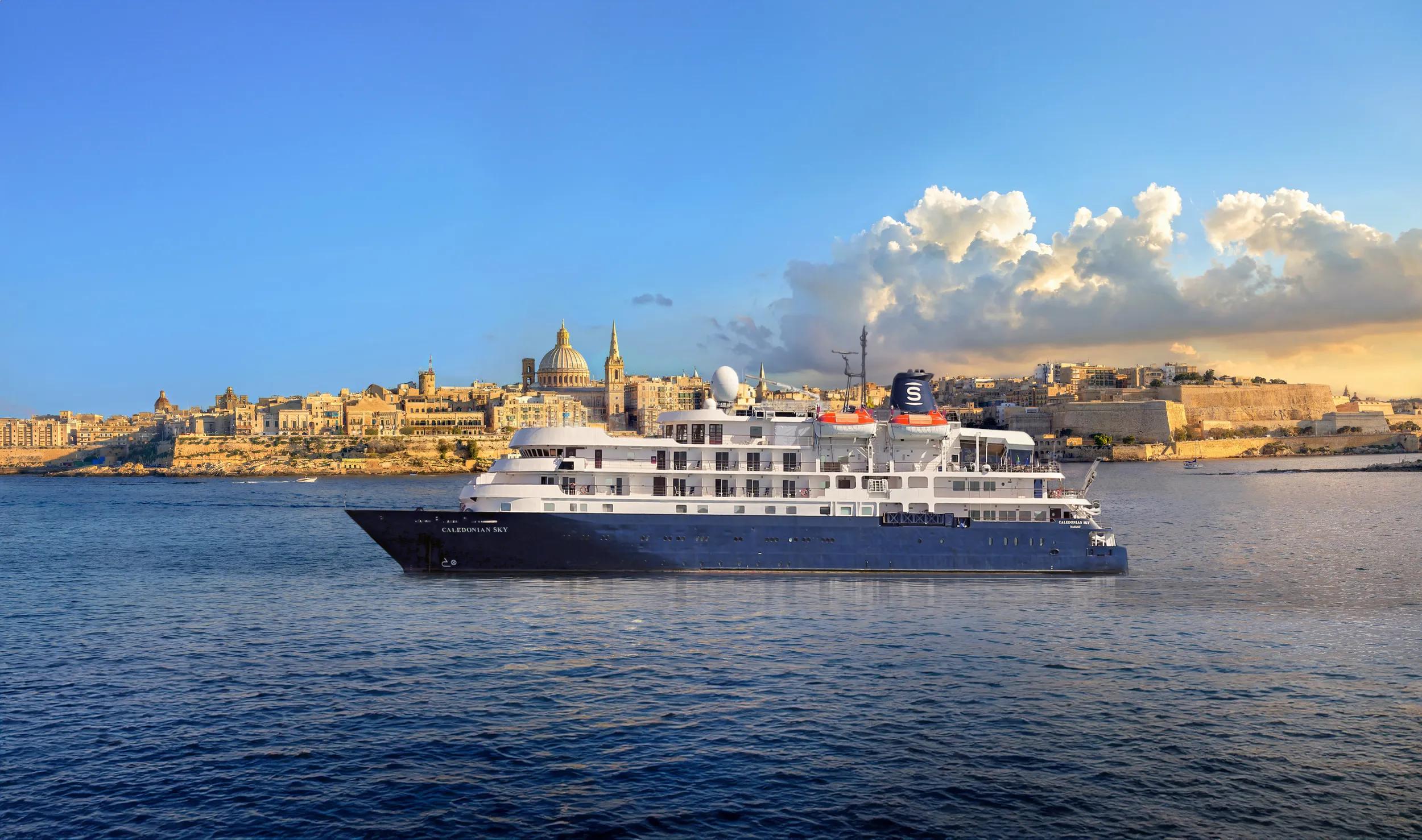 The ship Caledonian Sky and panoramic view of Valletta waterfront with Carmelite Church dome and St. Pauls Anglican Cathedral at sunset,  Malta