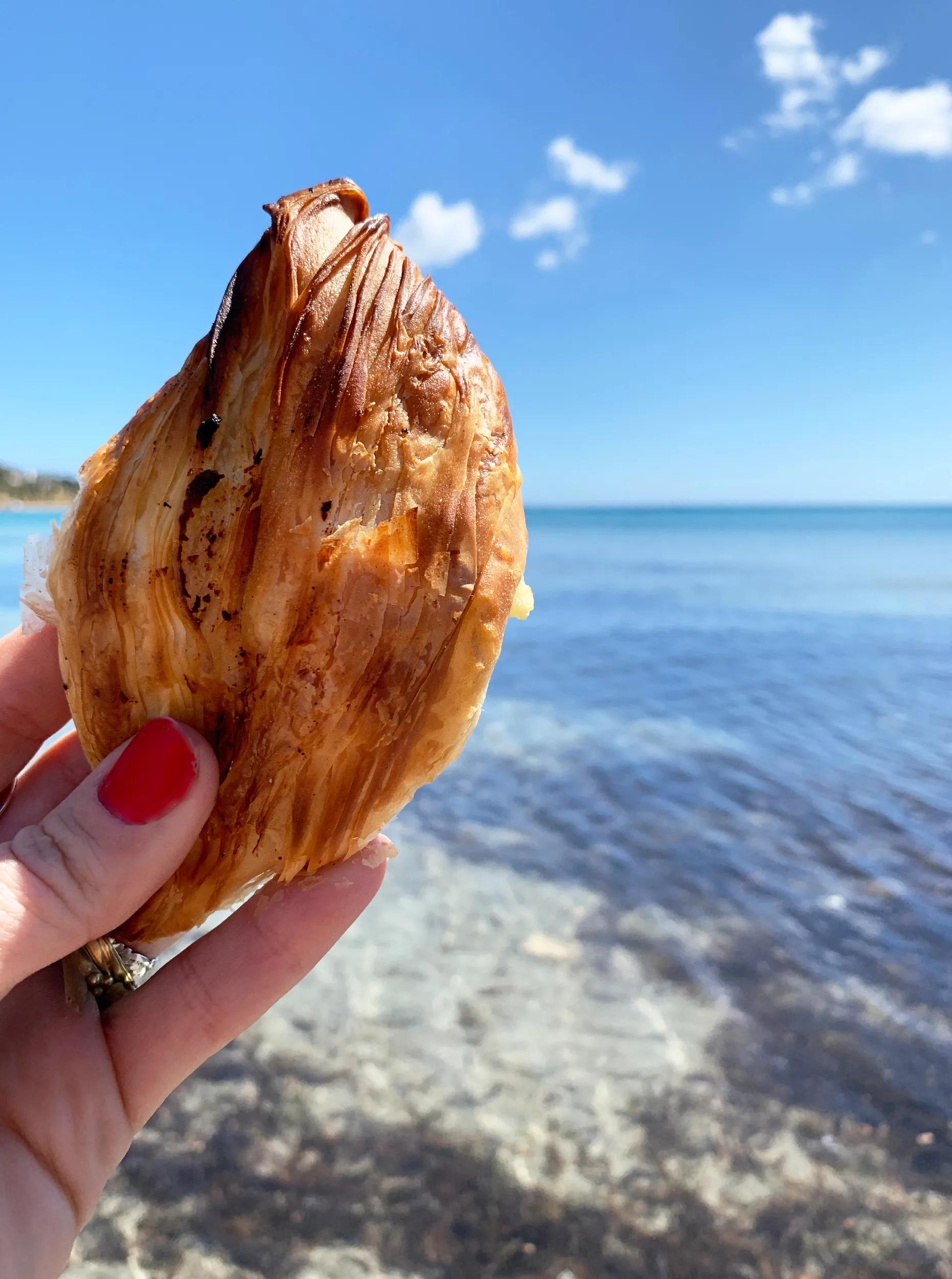 Pastizzi, National Street Food in Malta, Pastizz in Woman Hand on sea Background. Maltese cuisine