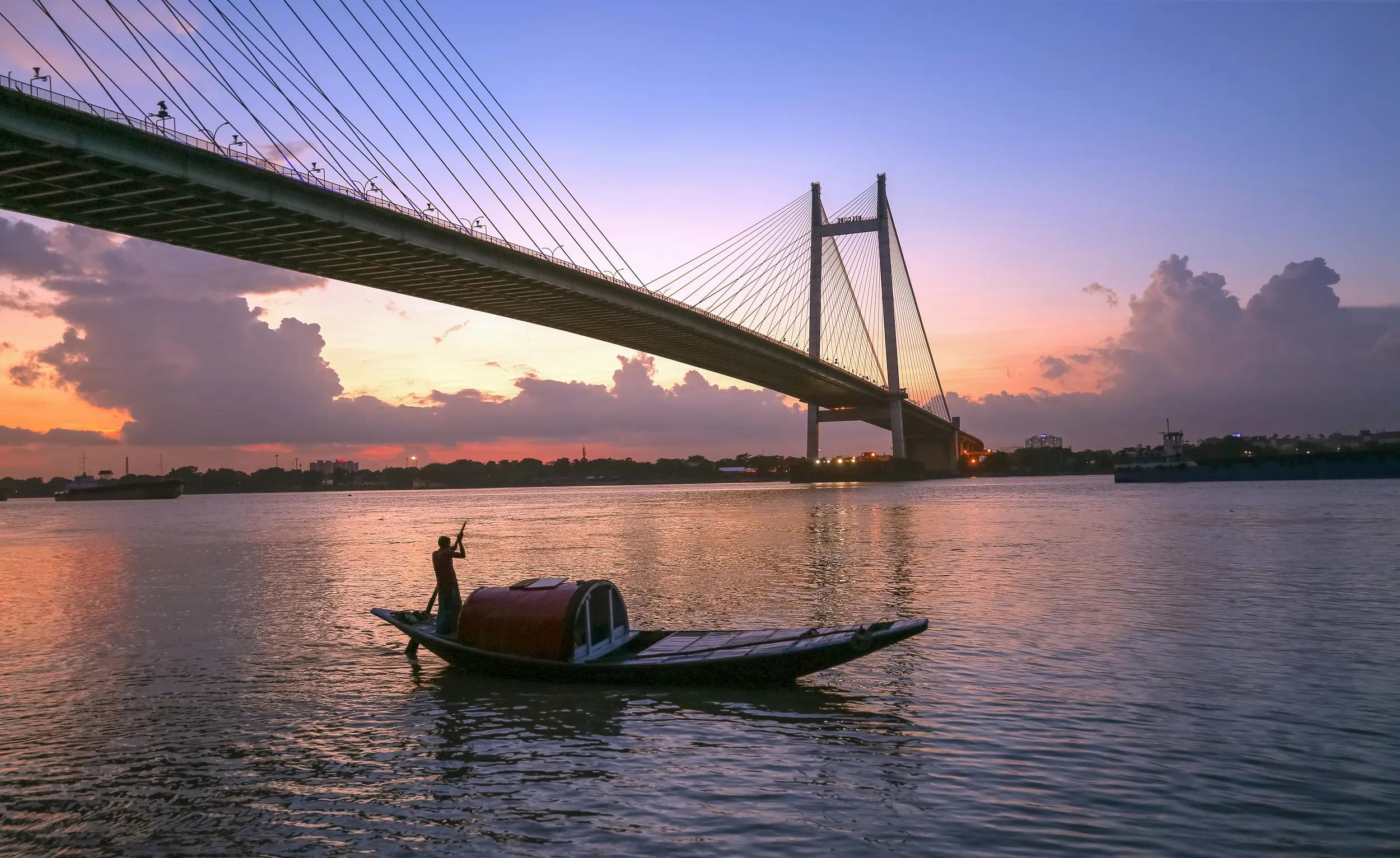 Cable stayed bridge at Kolkata India known as the Vidyasagar Setu built on the river Ganges at twilight with view of a wooden country boat