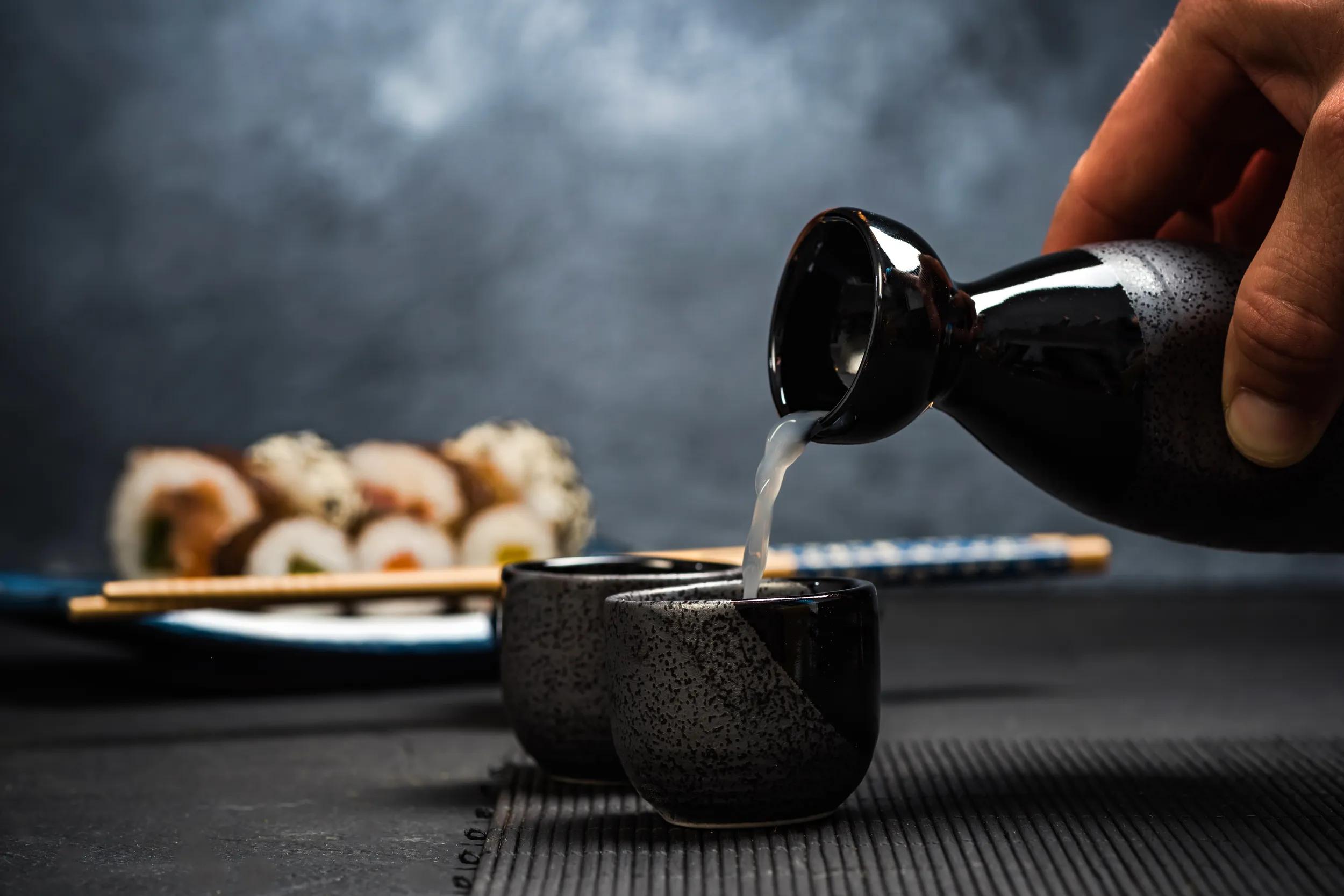 Man pouring sake into sipping bowl.