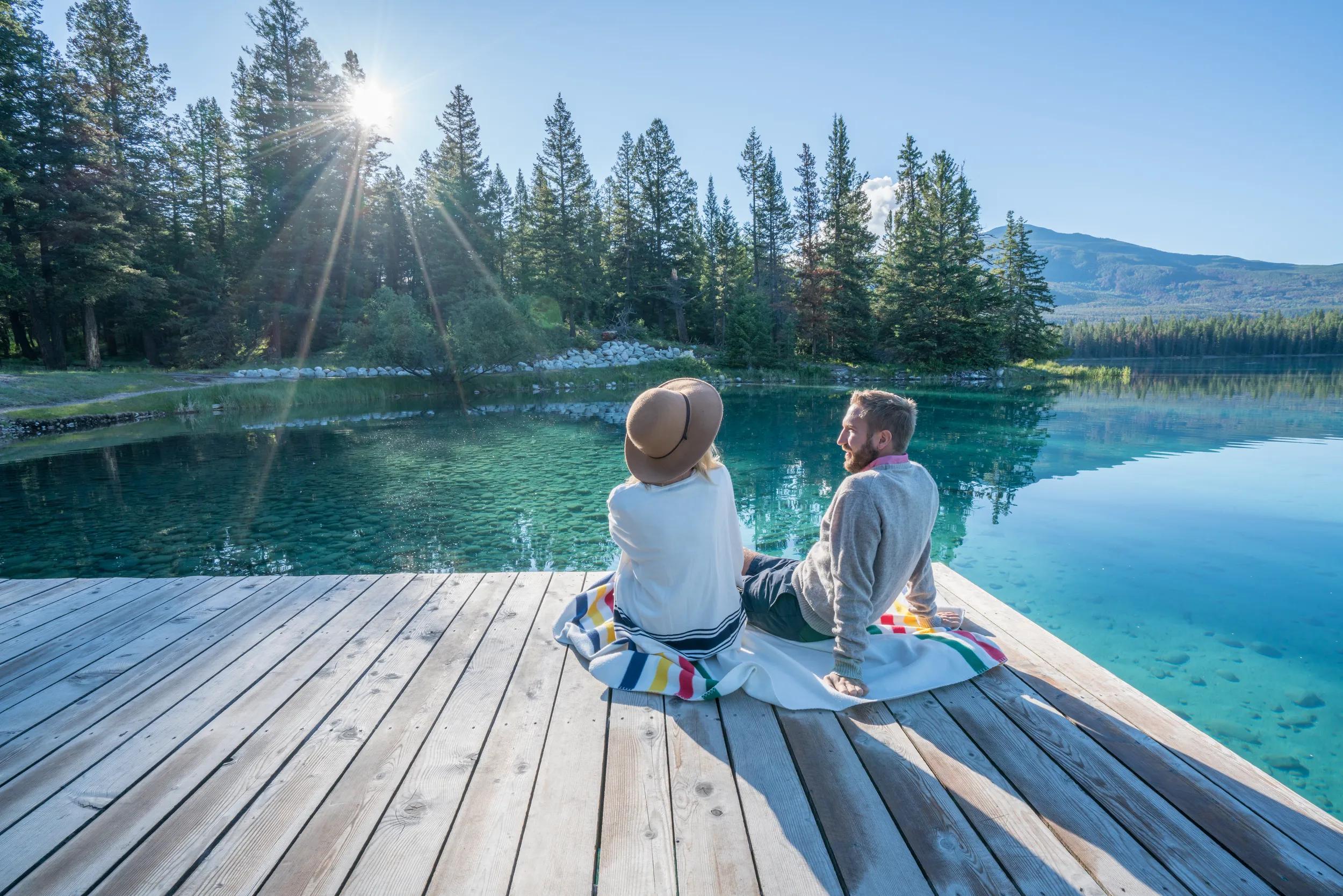 Cheerful young couple sitting on lake pier and sharing some relaxing moments.
