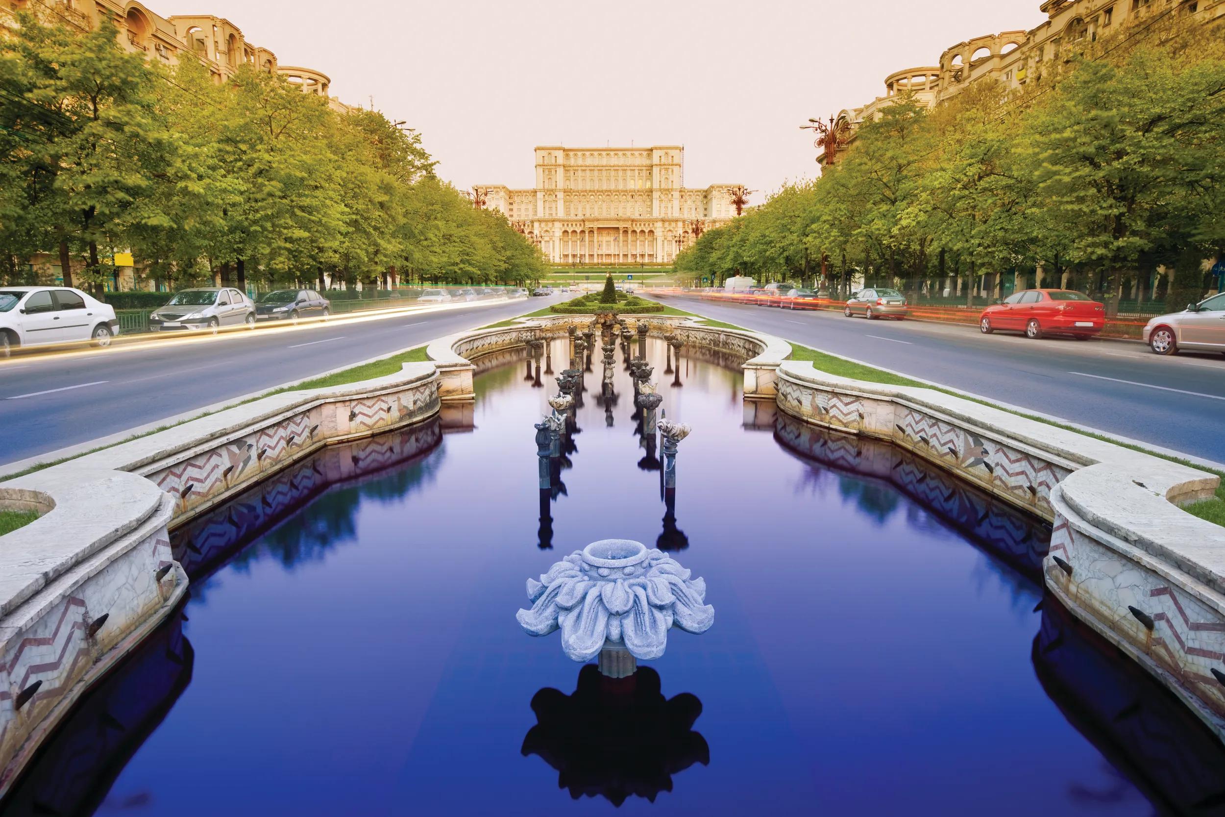 Fountains along the tree-lined Bulevardul Unirii, a major thoroughfare in central Bucharest, with the Palace of the Parliament in the background.
