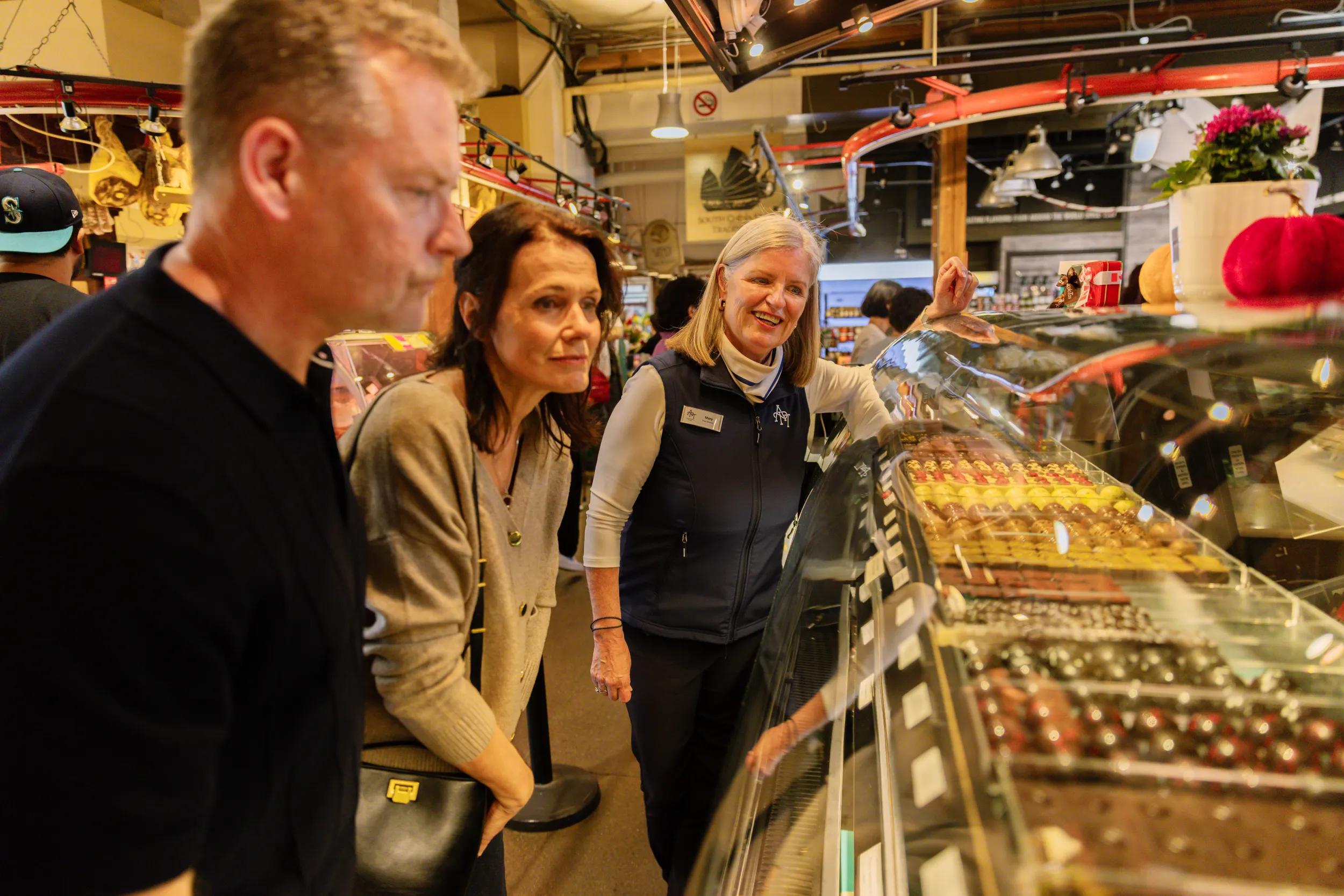 Guest couple with APT Tour Director at Public Market, interior, Granville Island, Vancouver, Canada.