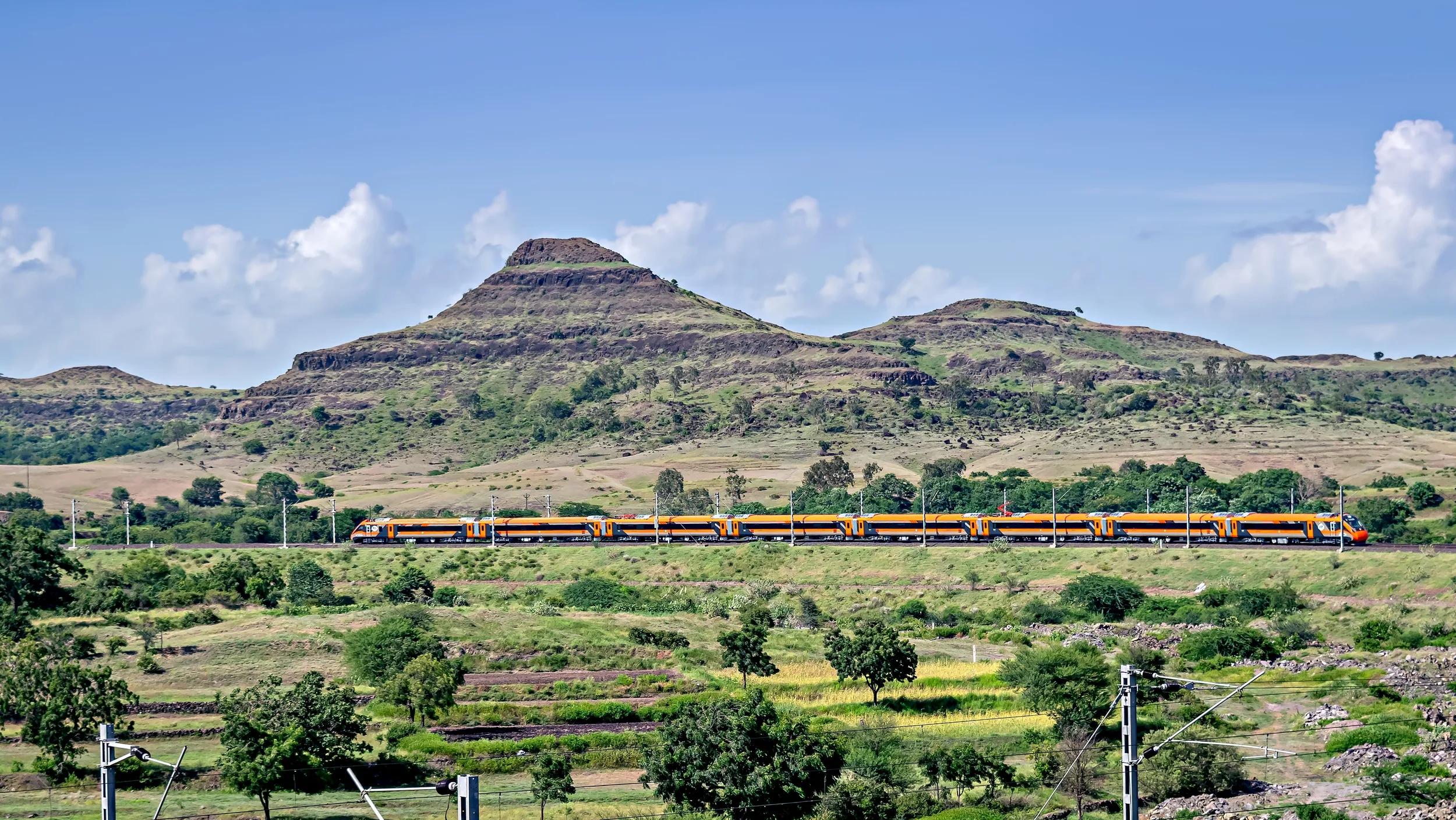 India's first indigenous development semi high speed orange Vande Bharat express , also known as train 18 , at a scenic location.