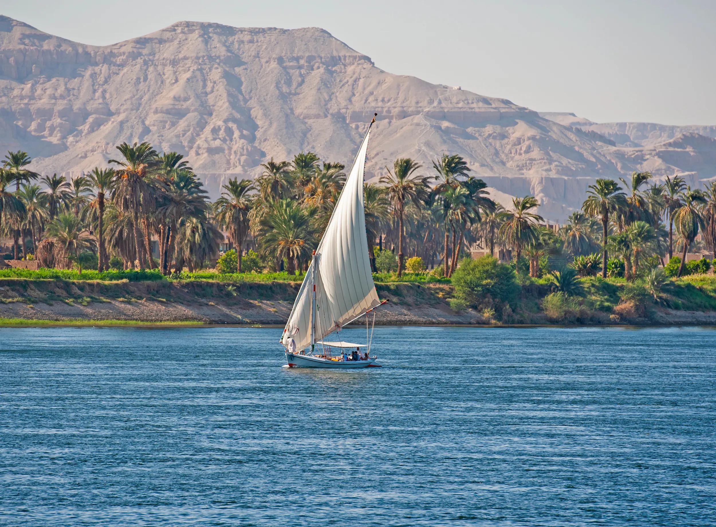 Traditional Egyptian felluca river boat sailing on the Nile with Luxor west bank in background