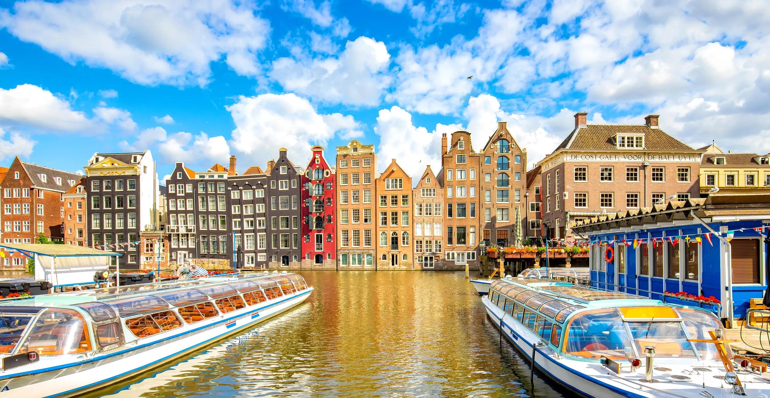 Amsterdam city skyline and colorful houses over Damrak canal, Netherlands.