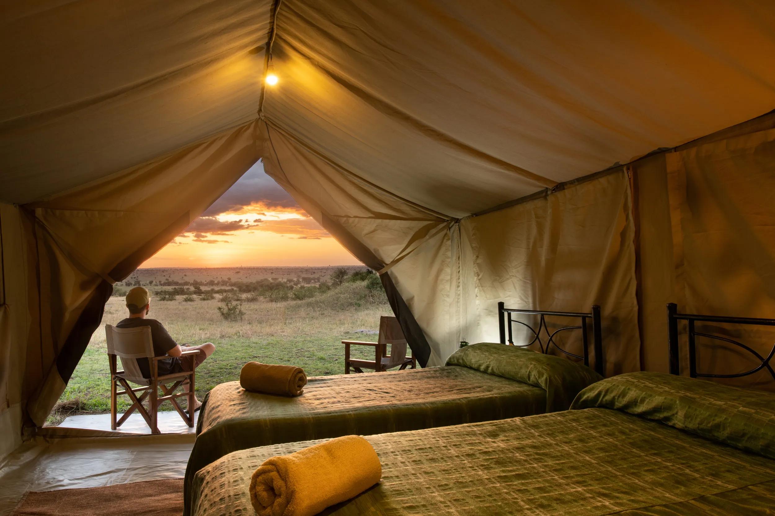Man in tent watching sunset. Kati Kati Camp is a mobile camp situated in central Serengeti.