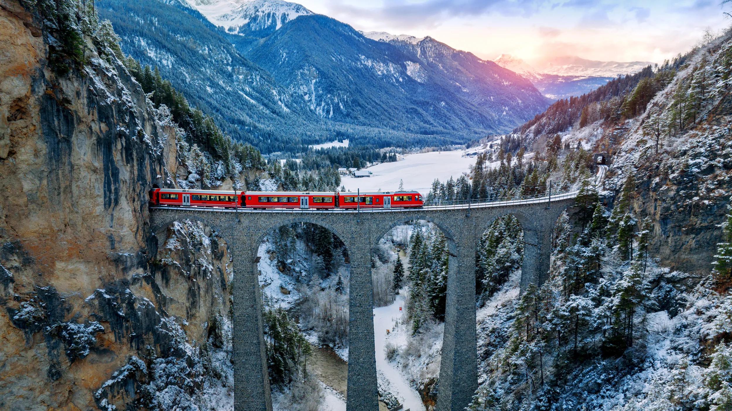 Aerial view of Train passing through famous mountain in Filisur, Switzerland. Landwasser Viaduct world heritage with train express in Swiss Alps snow winter scenery.