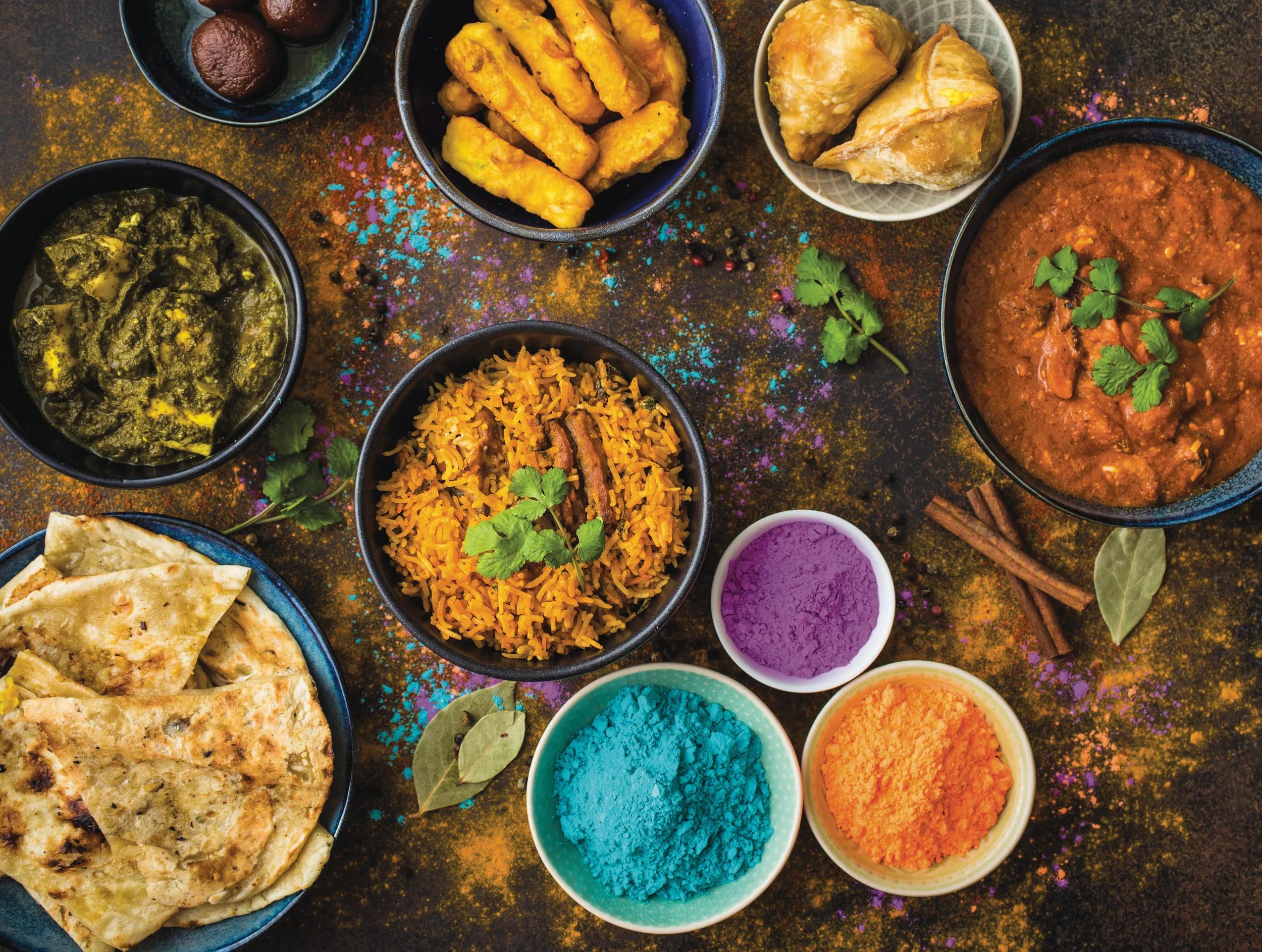 Traditional Indian food, Holi colours powder, rustic background. Indian Holi holiday. Indian dishes and snacks set. Holi celebration. Top view. Festive Indian table setting. Party food selection