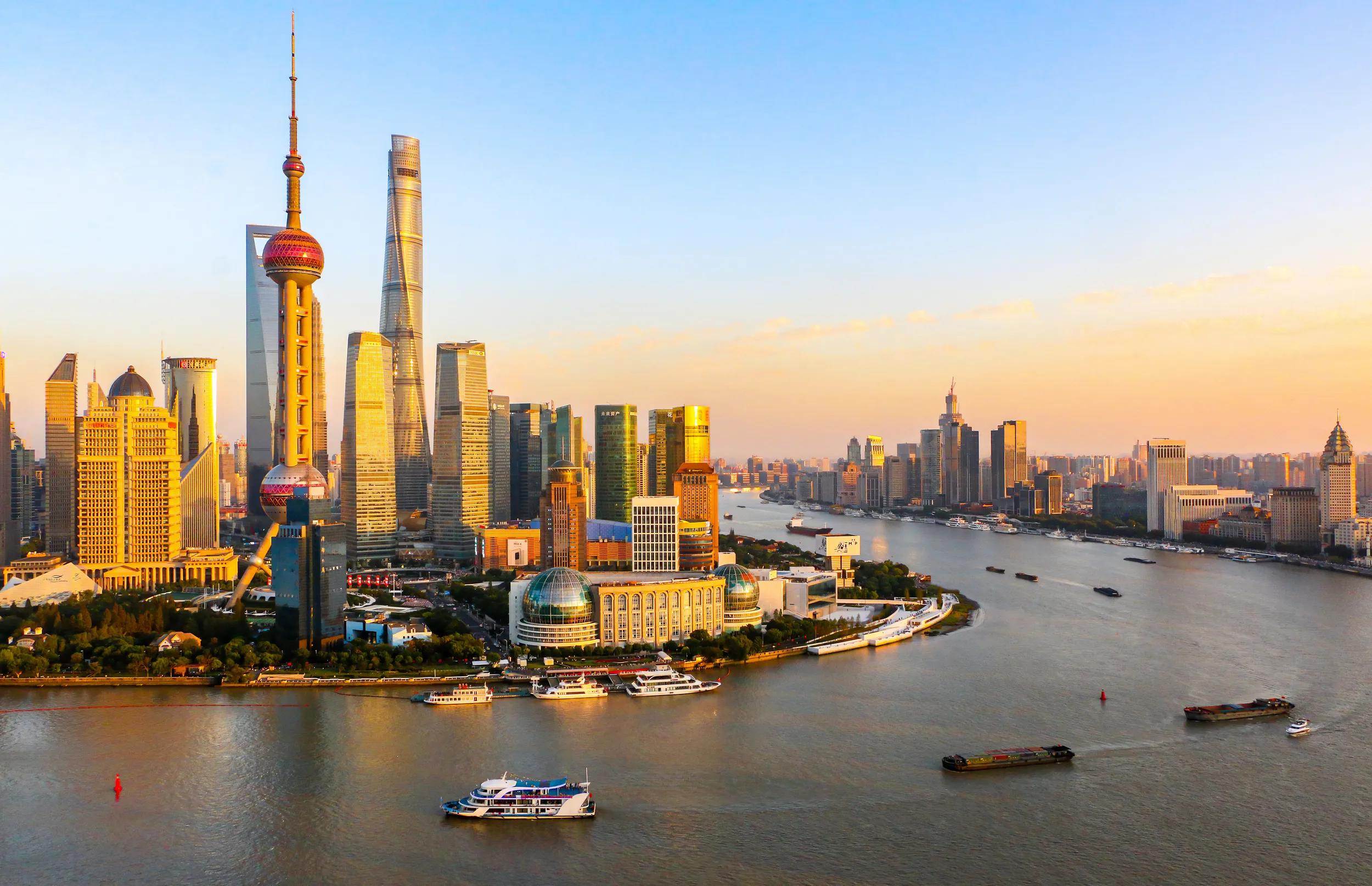Skyline and cityscape of Shanghai as cruise ships and cargo ships cross the Huangpu River passing the Oriental Pearl Tower and Shanghai Tower, CHina