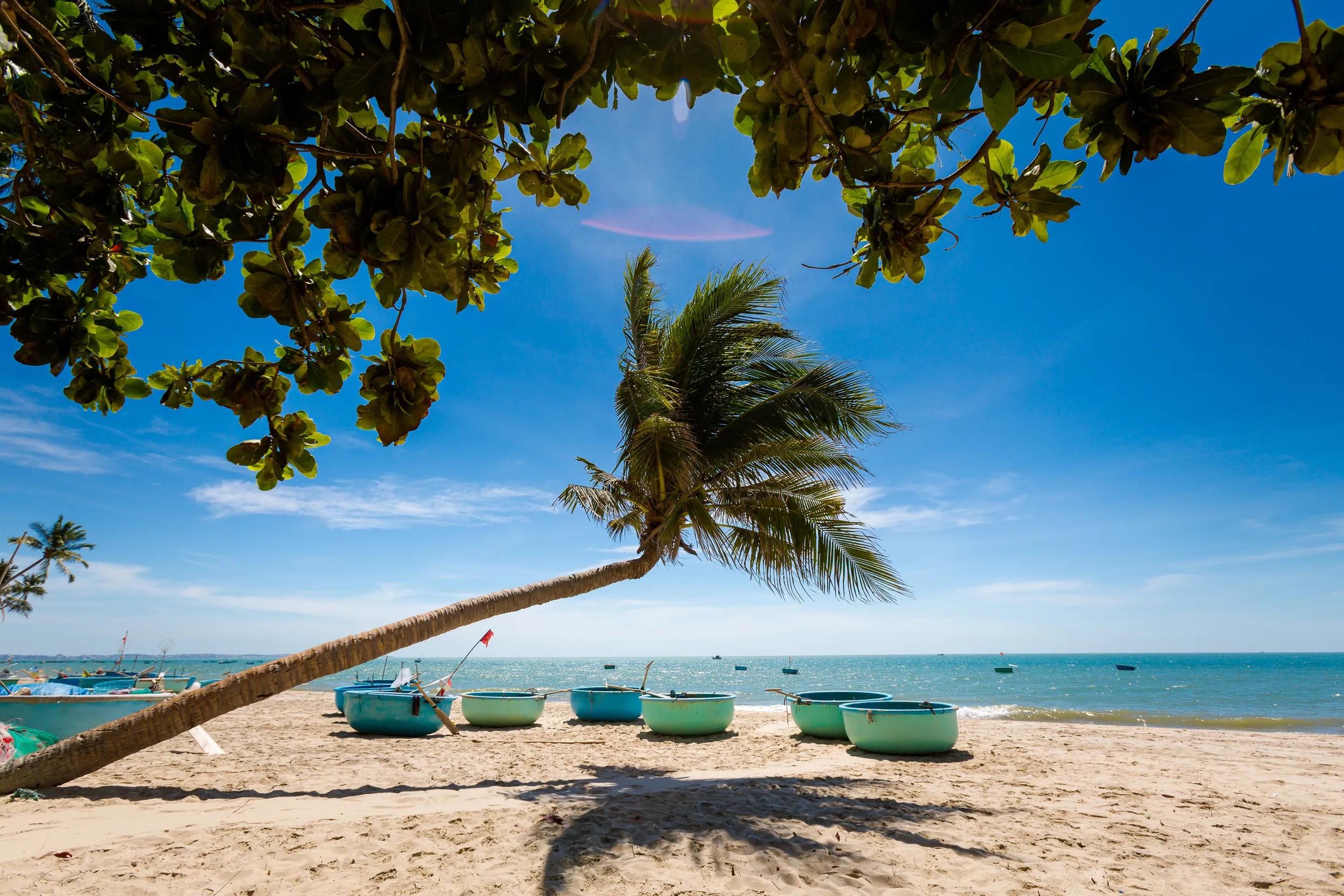 Vietnam coastal motorbike trip stop in Mui Ne, Phan Tiet region. Vietnamese corracles on the beach and in the sea.