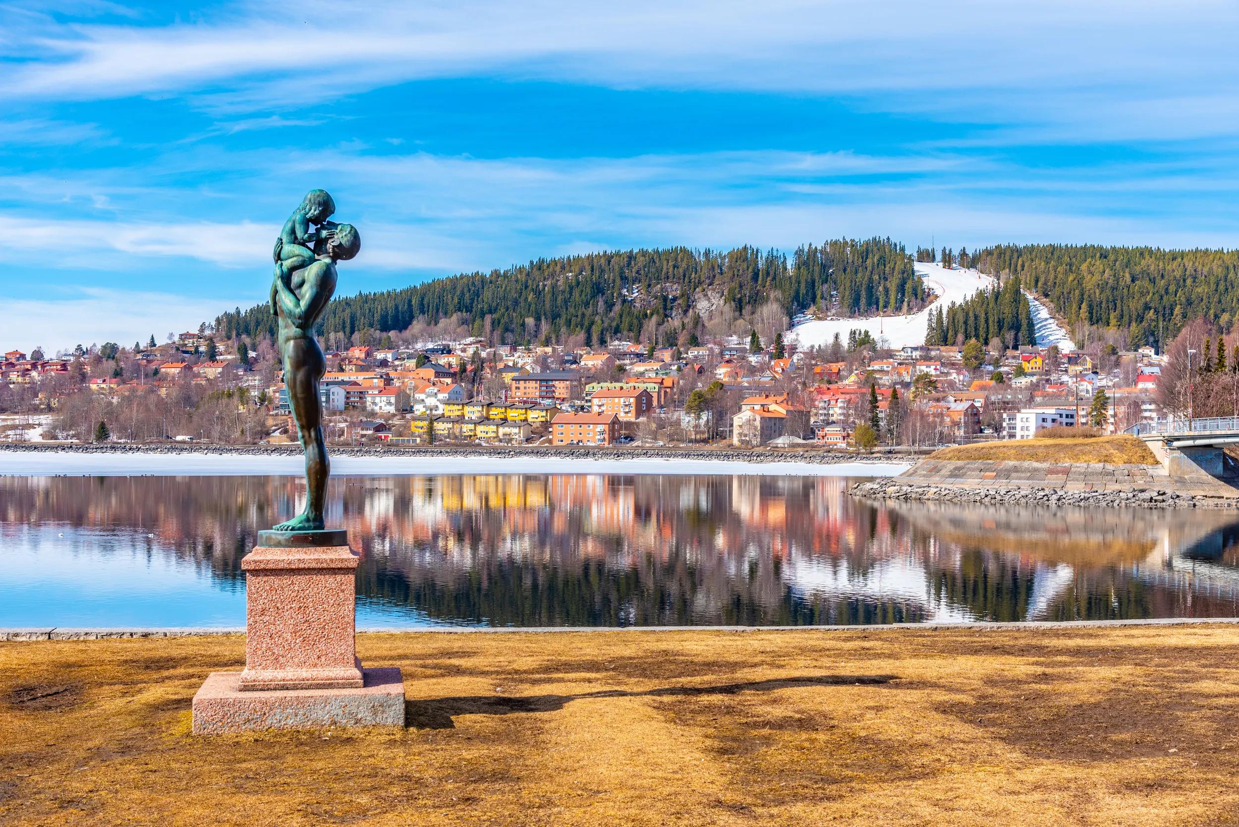 Skyline of Ostersund, Sweden on a lake with a bronze statue of a naked father and child.