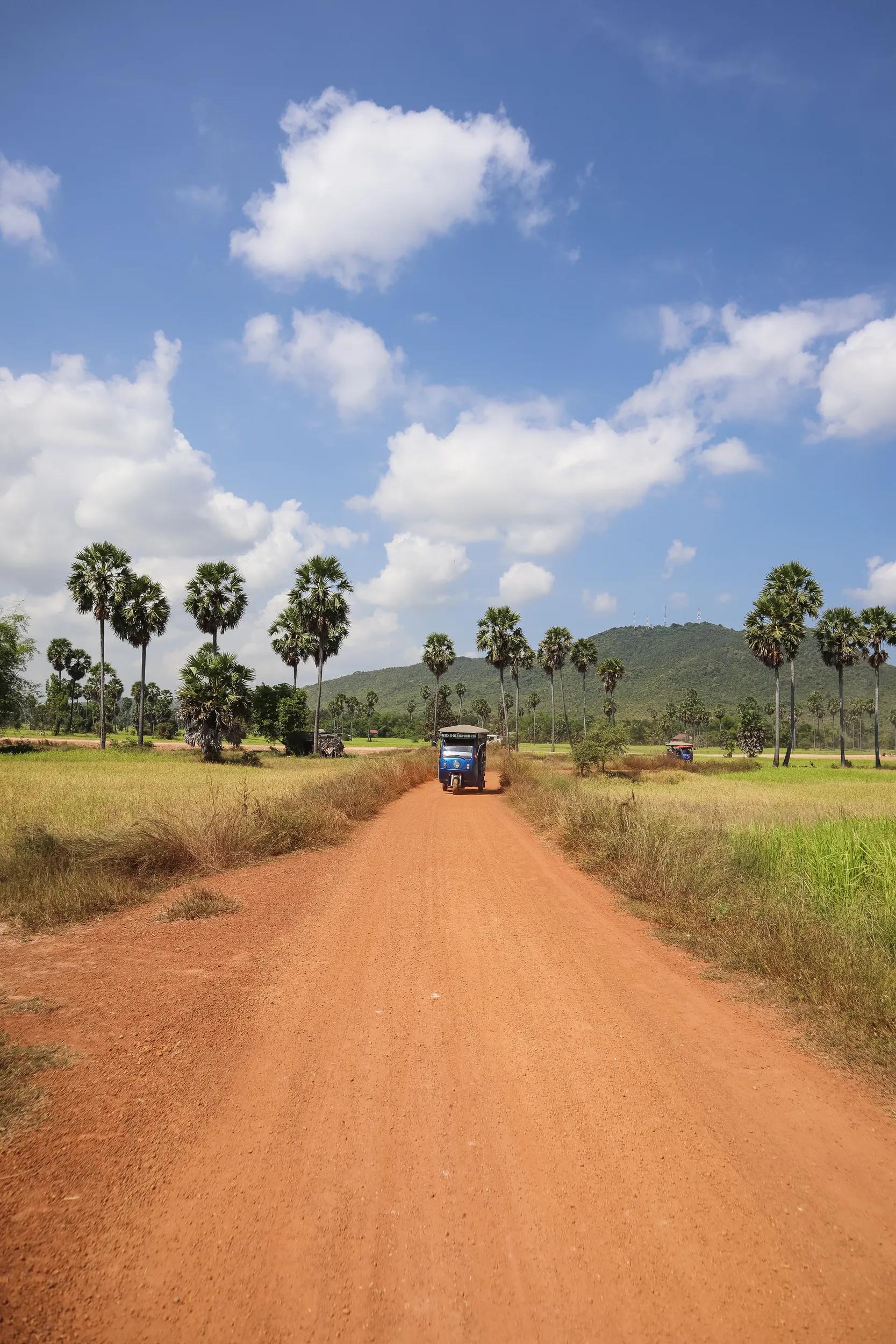 tuk tuk driving along dirt road