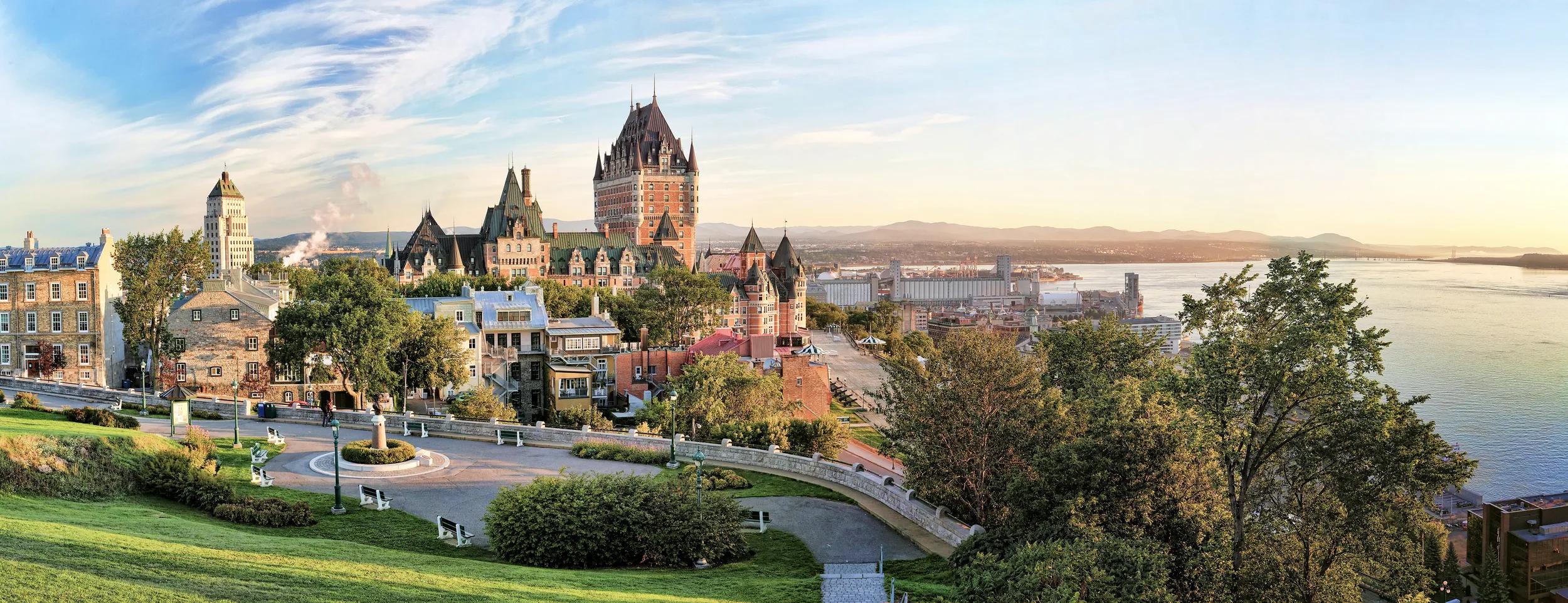 A panoramic view of Chateau Frontenac surrounded by greenery in Old Quebec, Canada at sunrise