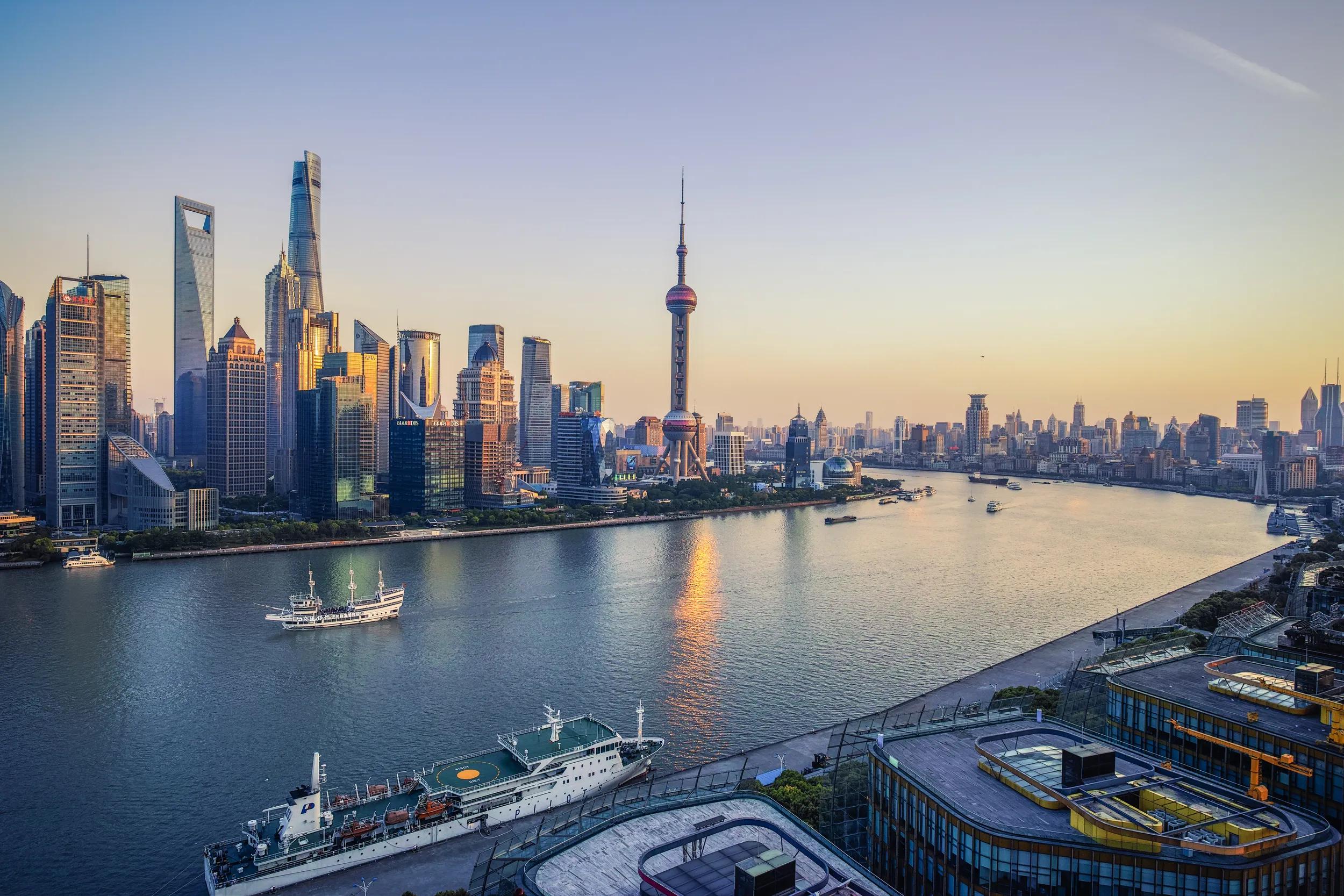 Skyline and cityscape of Shanghai as cruise ships and cargo ships cross the Huangpu River passing the Oriental Pearl Tower and Shanghai Tower, CHina