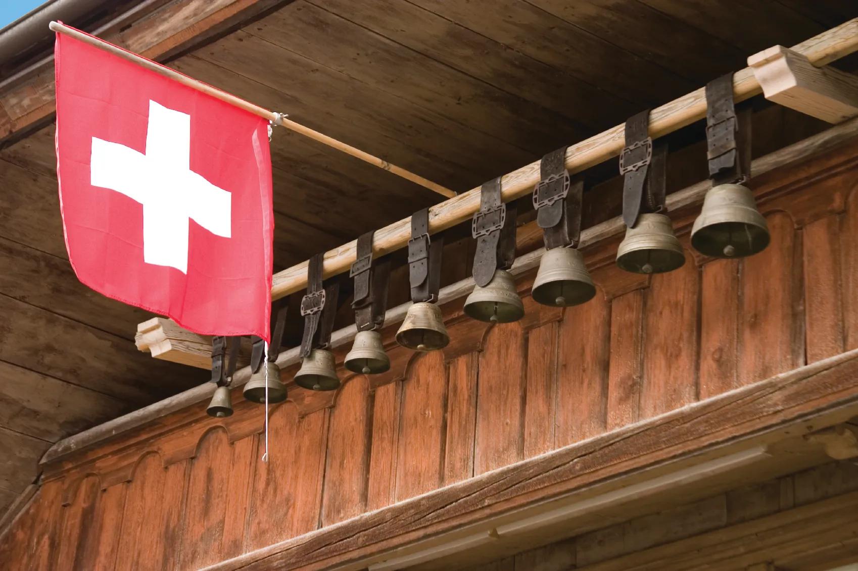 Cowbells and Swiss flag hanging in front of Swiss chalet in Gruyeres.