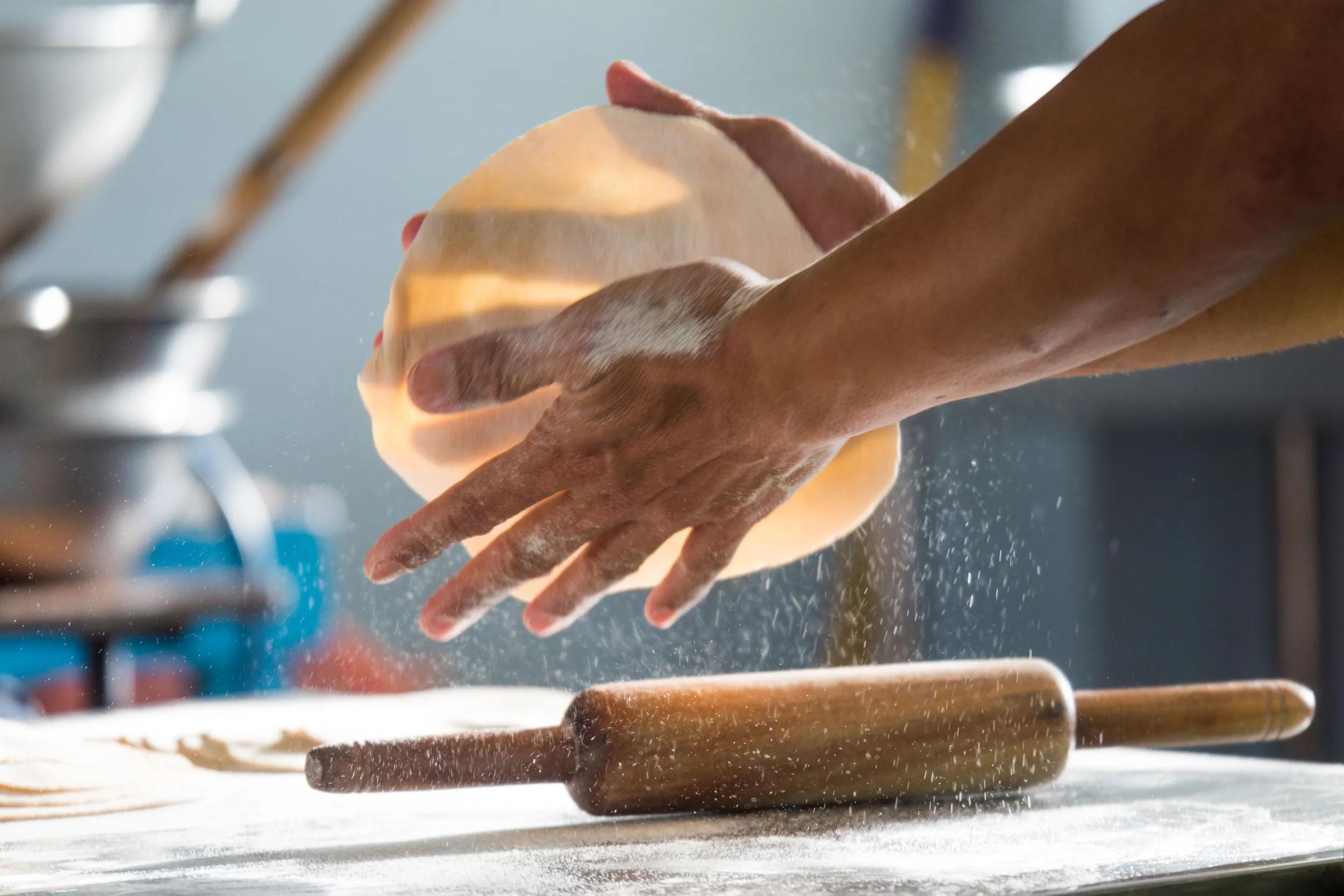 A closeup shot of a man making roti flatbread in a kitchen