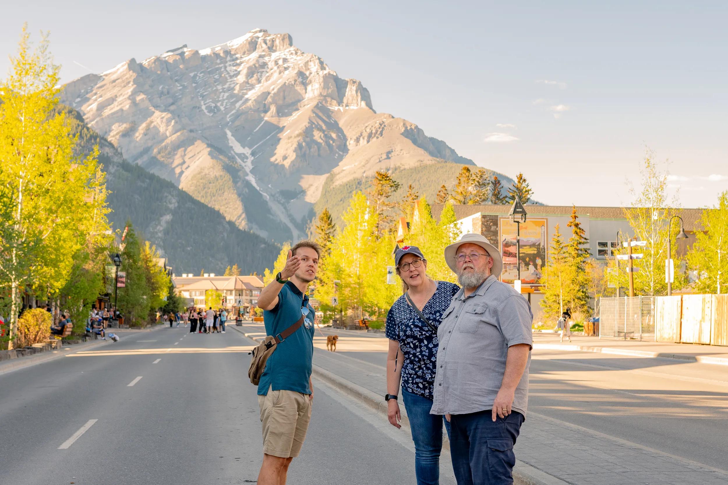 Wide shot of a senior couple walking through the tourist town of Banff and asking for directions. They are enjoying a nice spring/summer day and the scenic landscape.
