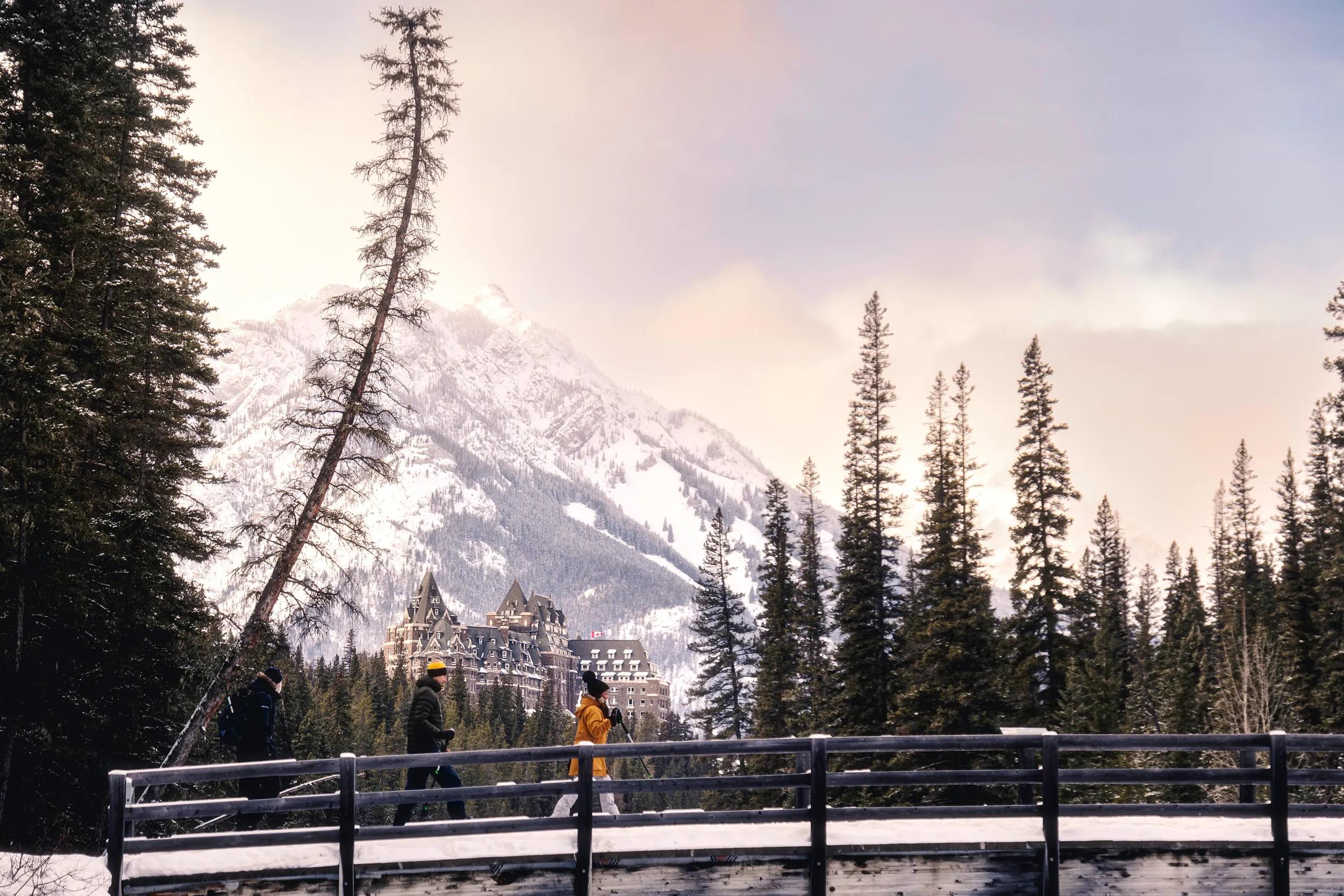 People walking in the snow over bridge near Fairmont Banff Springs Hotel, Banff, Canada.