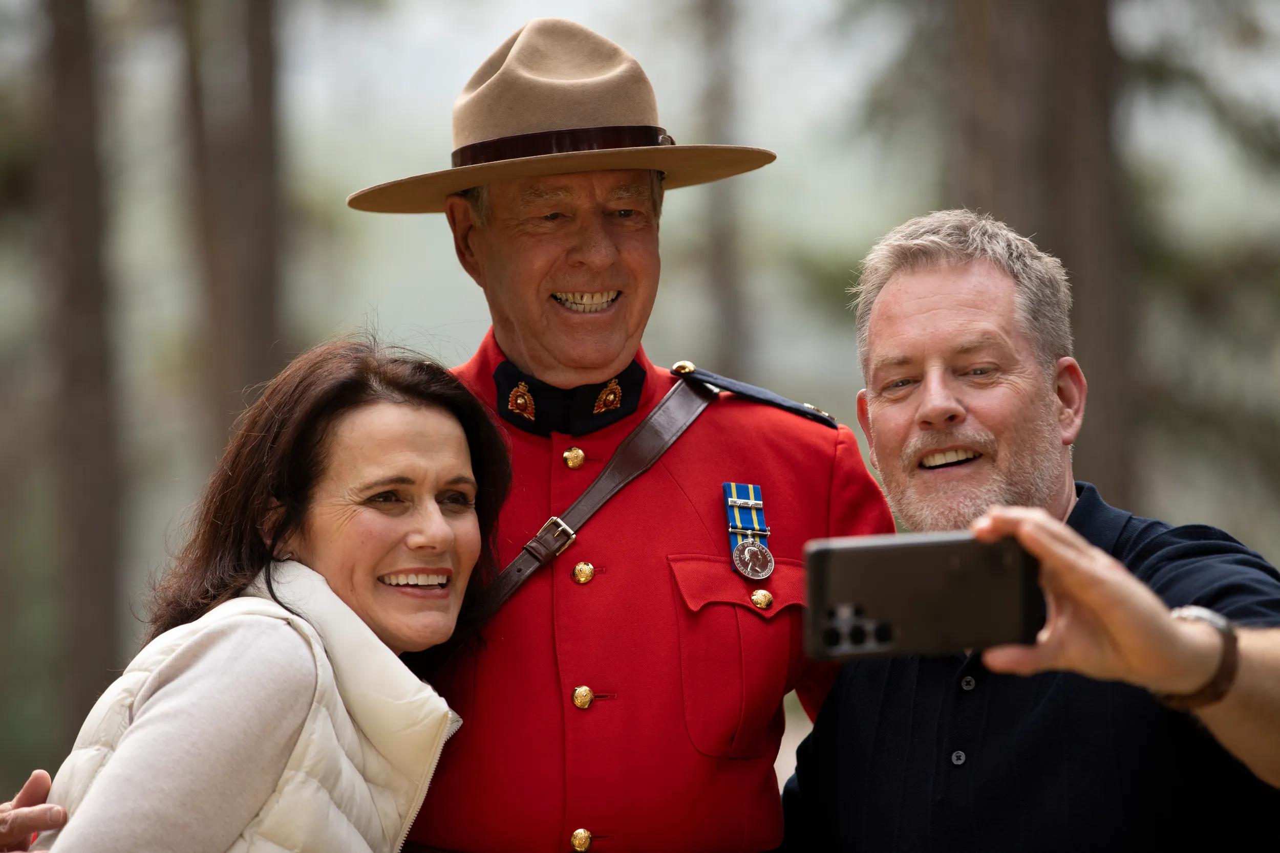 Couple take a selfie with a Canadian Mountie, Meet a Mountie experience, Banff National Park, Canada.