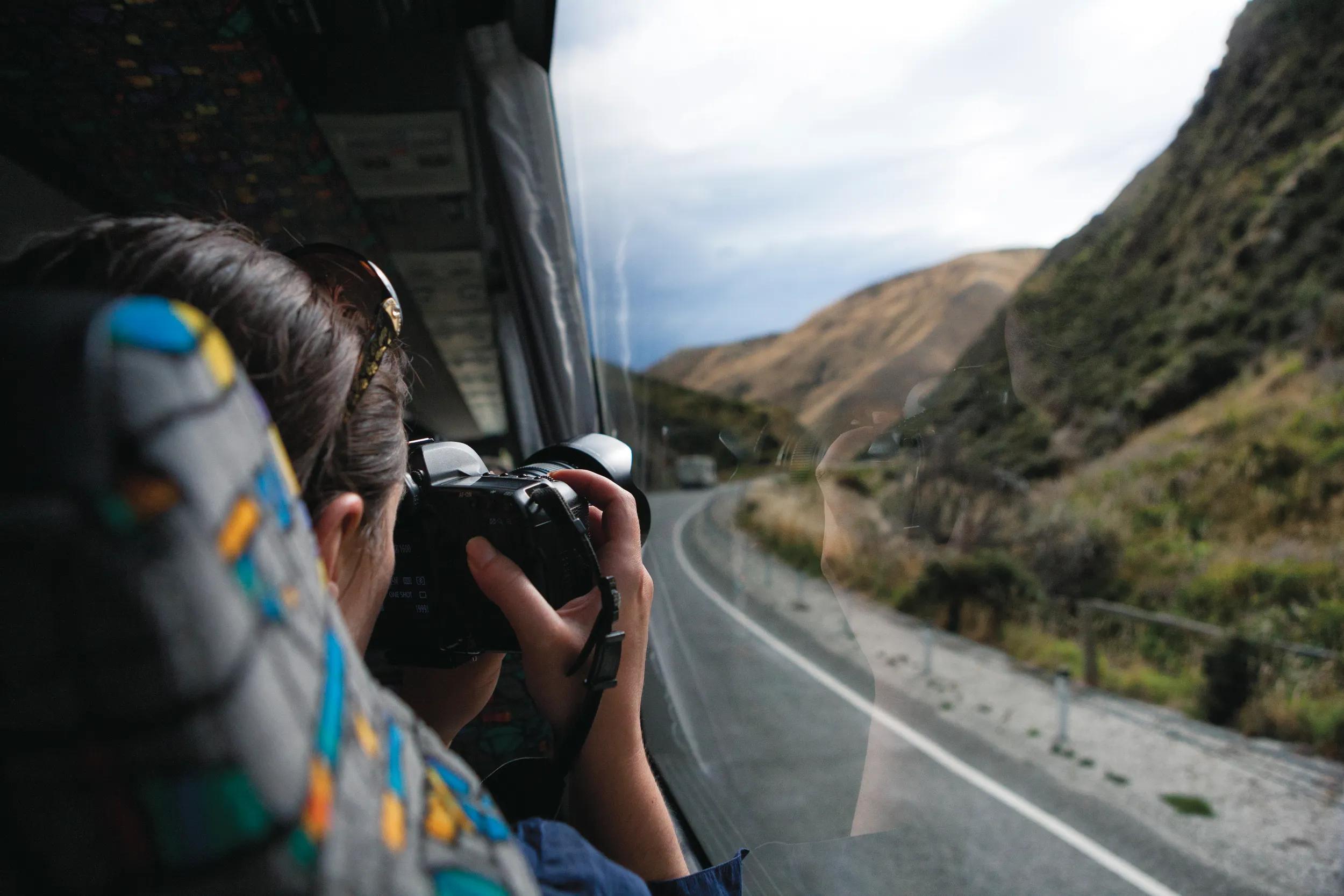 Tourist taking photographs from a bus traveling through the Southern Alps mountains of New Zealand.