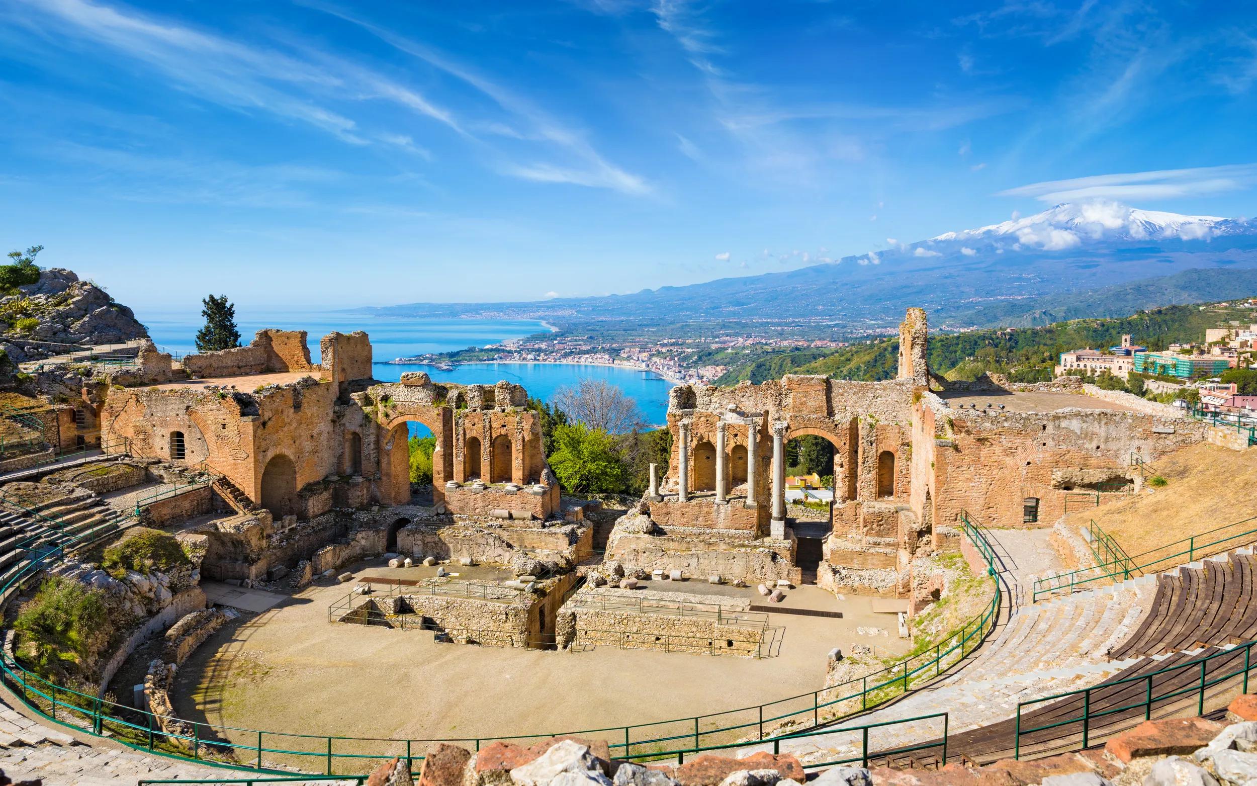 Ruins of Ancient Greek theatre in Taormina on background of Etna Volcano, Italy. Taormina located in Metropolitan City of Messina, on east coast of island of Sicily.