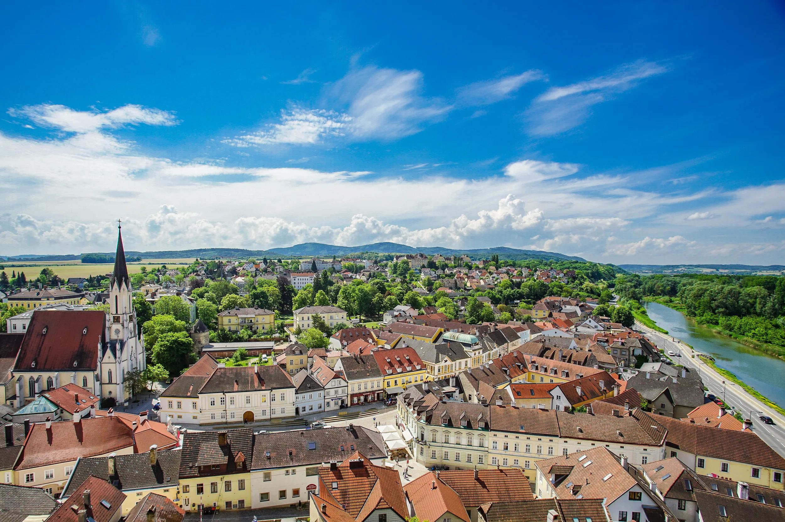 The image shows the town of Melk, west of Vienna on the Danube River from a height overlooking the town on a sunny day