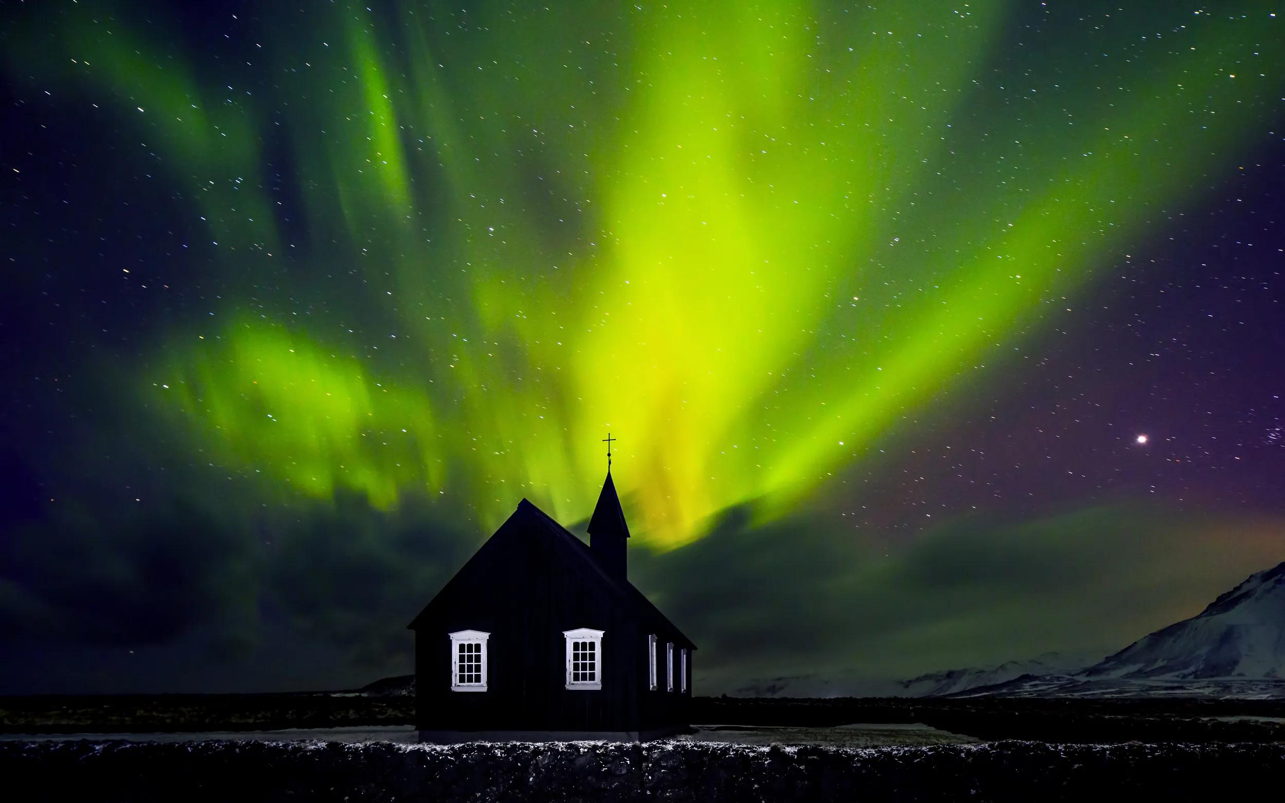 Beautiful bright green Northern light over church, little village in the Iceland, amazing forces of nature, wonderful night sky landscape
