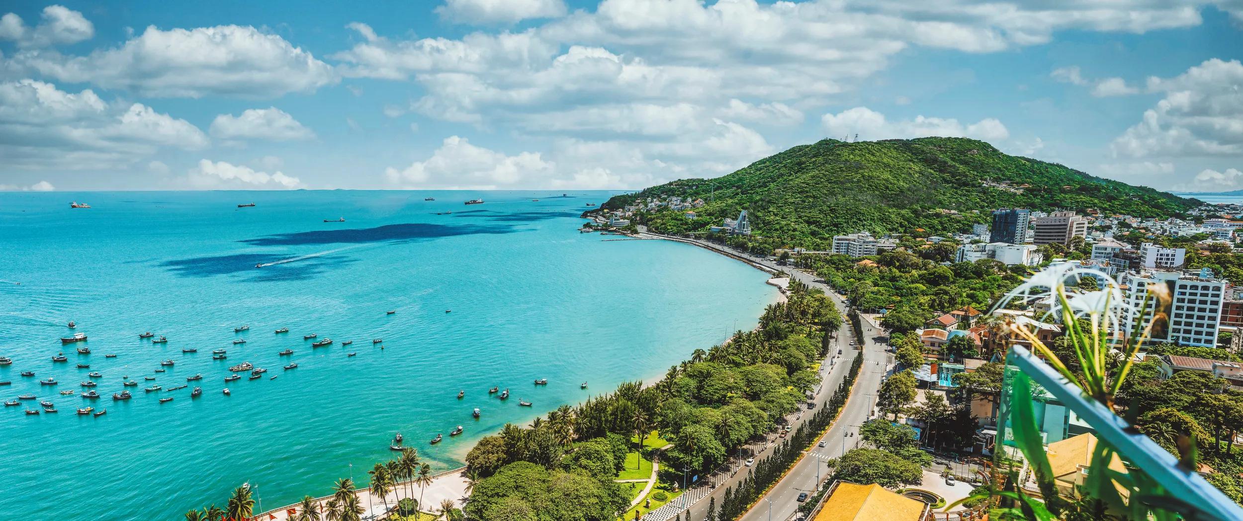 Panoramic coastal Vung Tau view from above, with waves, coastline, streets, coconut trees and Tao Phung mountain in Vietnam
