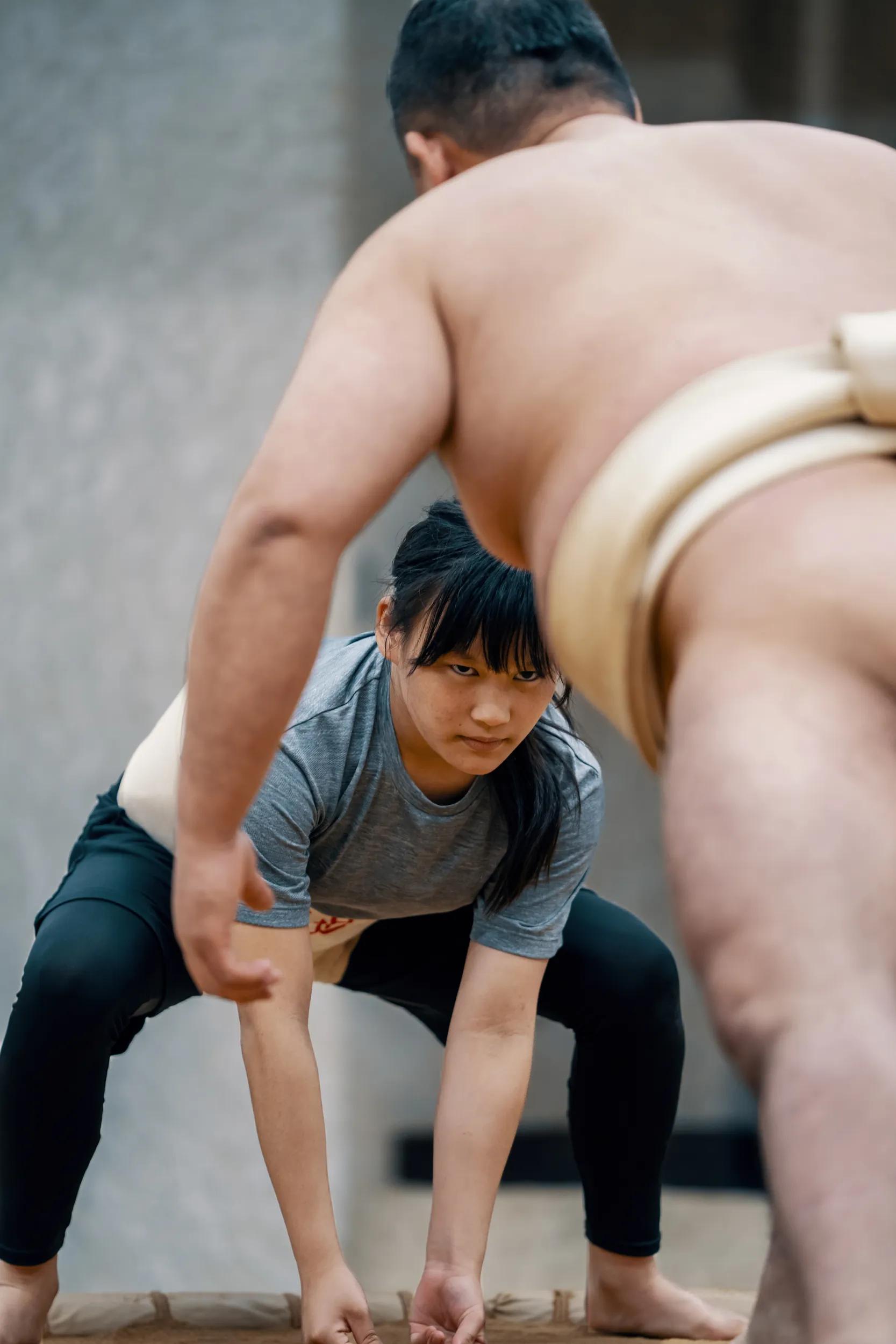 Young elementary-aged girl wrestling with her coach at a sumo practice in Japan