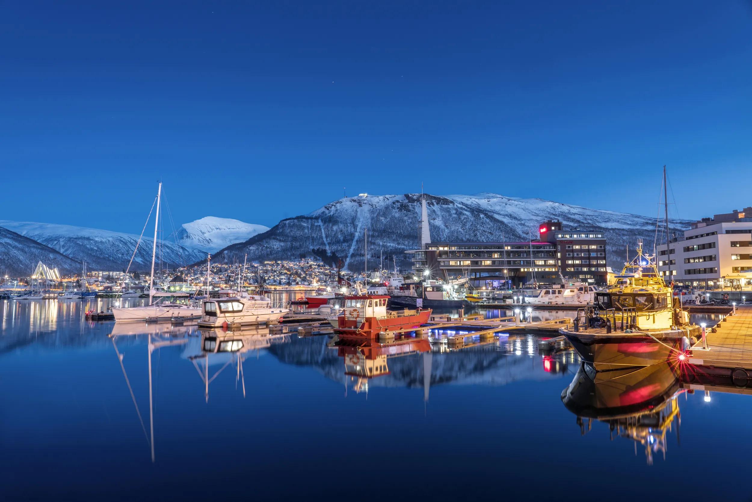 Beautiful winter landscape of picturesque harbor with fishing boat and traditional Norwegian rorbus in Tromso, Norway.