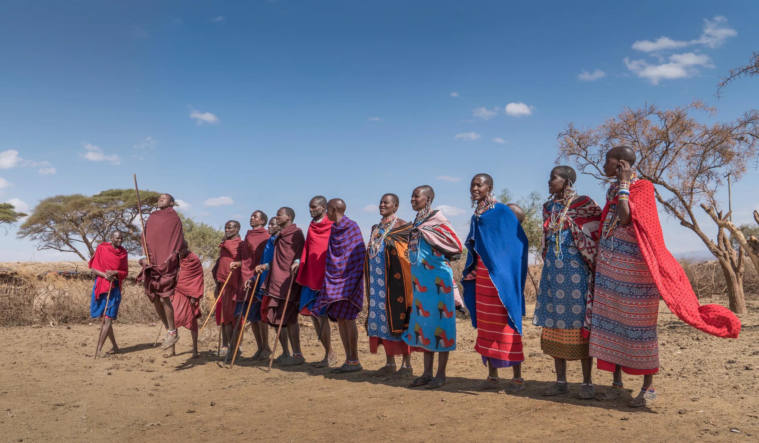 A group of Masai men and women with traditional clothes performing a traditional dance in a village near Amboseli National Park in Kenya.