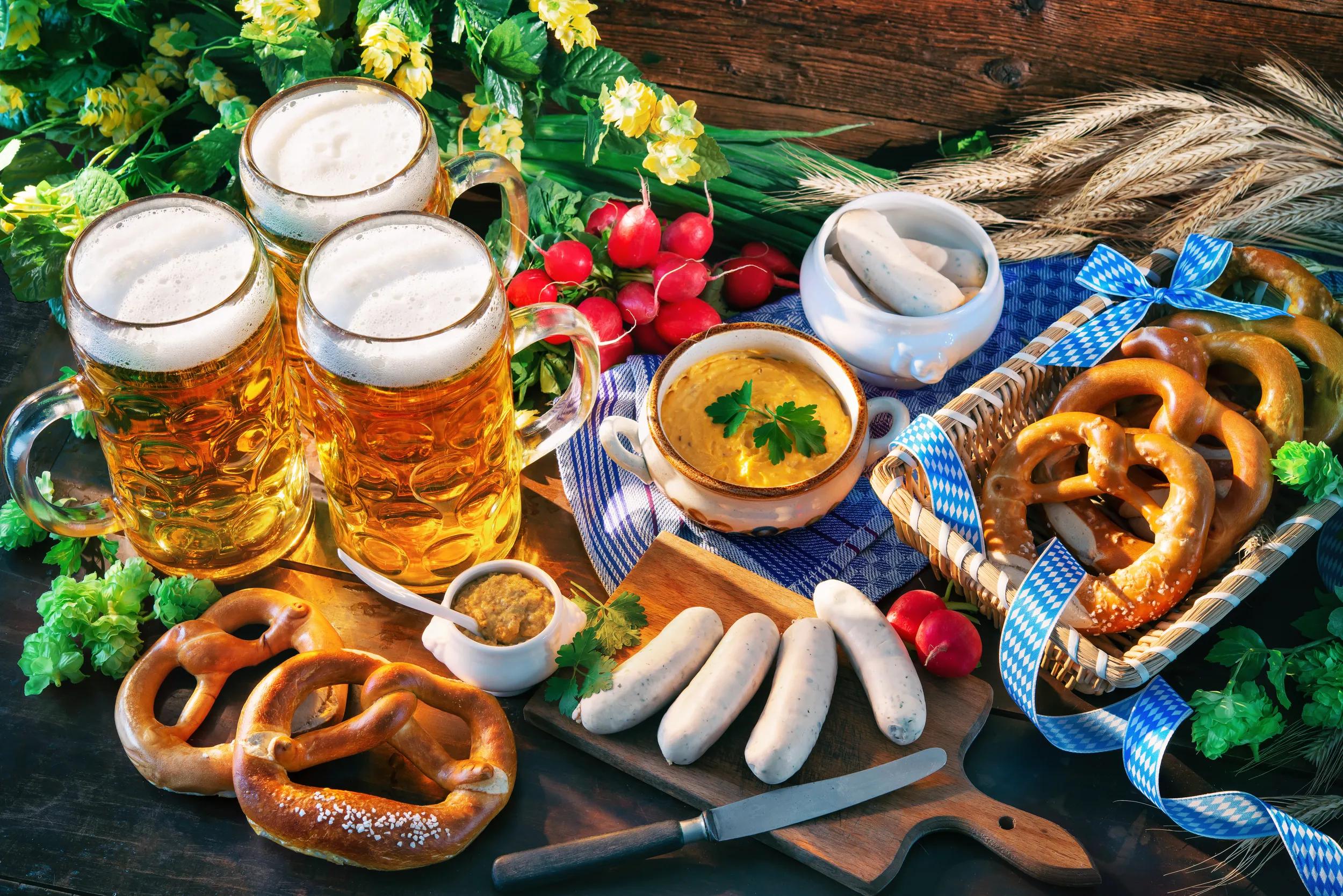 Bavarian sausages with pretzels, sweet mustard and beer mugs on rustic wooden table. Oktoberfest menu