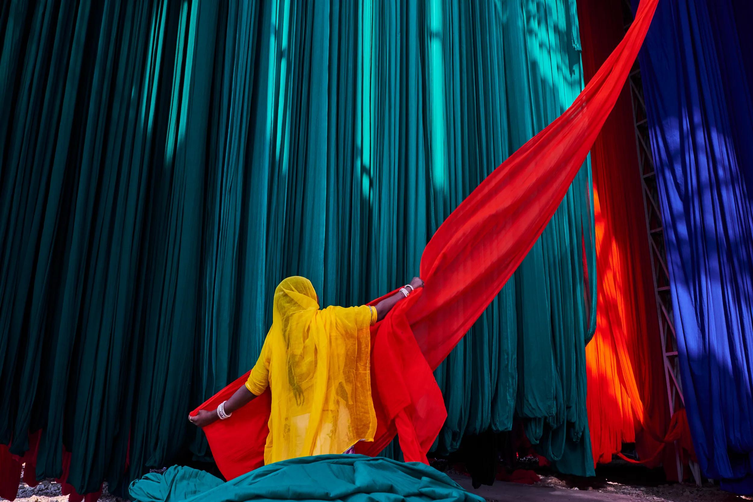 Woman drying textiles in open air in sari factory, Rajasthan, India.