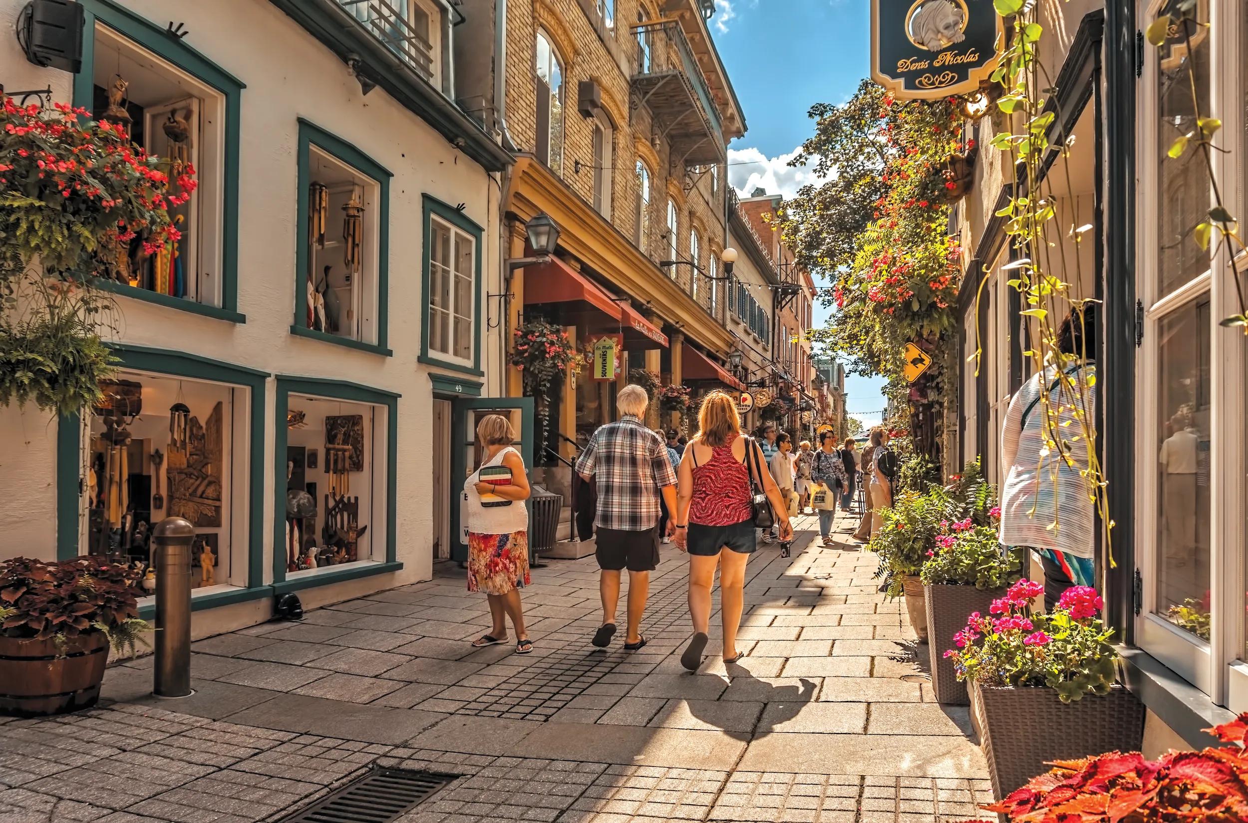 Quebec City, PQ, Canada - September 3, 2014 :A senior couple in summer casual shorts and tops walk hand in hand down rue de Petit Champlain in Quebec City's historic, romantic Lower Town taking in the shops and cafes on a warm late summer afternoon with a blue sky and clouds.