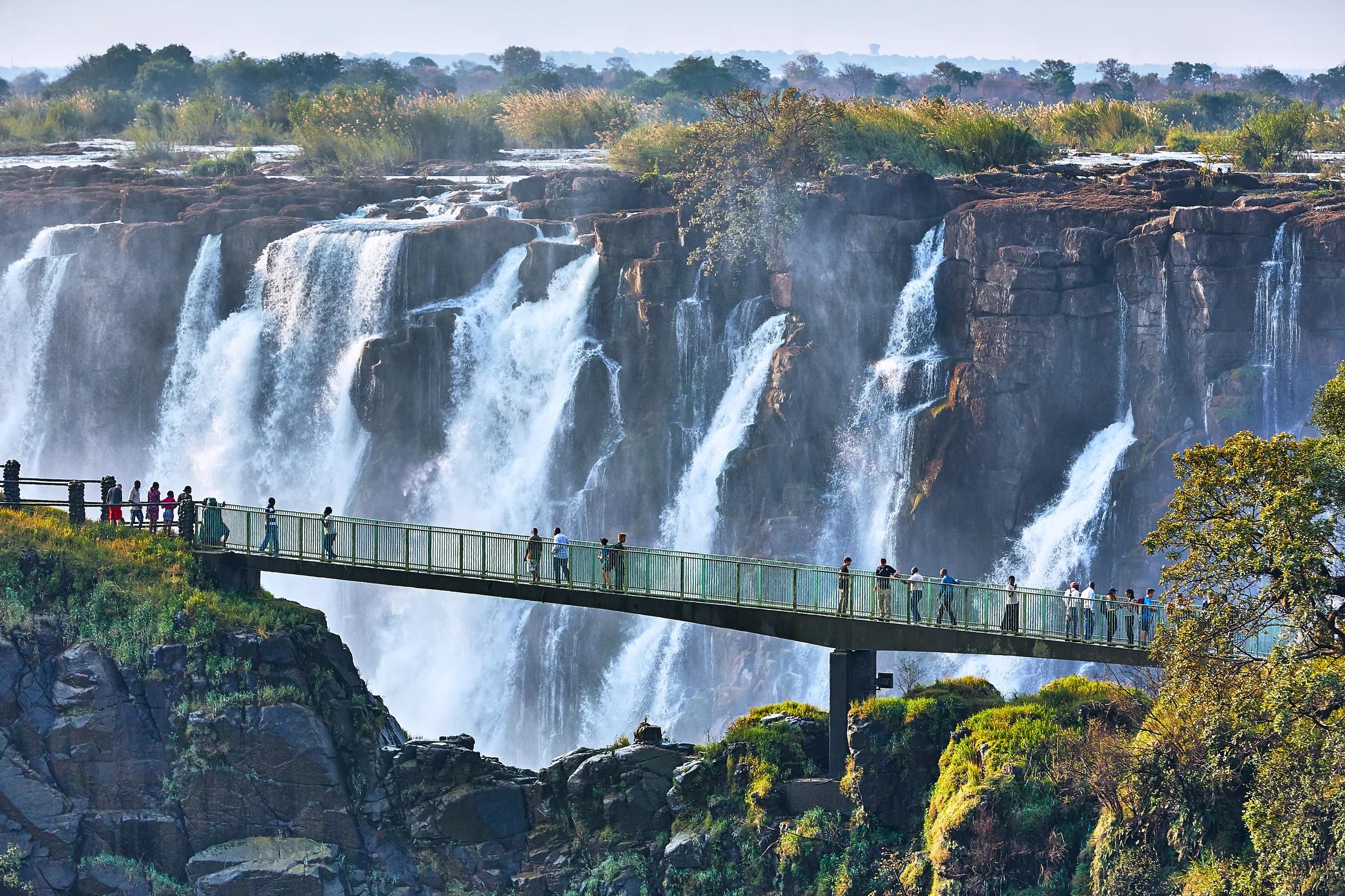 Tourists crossing the Knife Edge bridge on the Zambia side with the Mighty Victoria Falls in the background