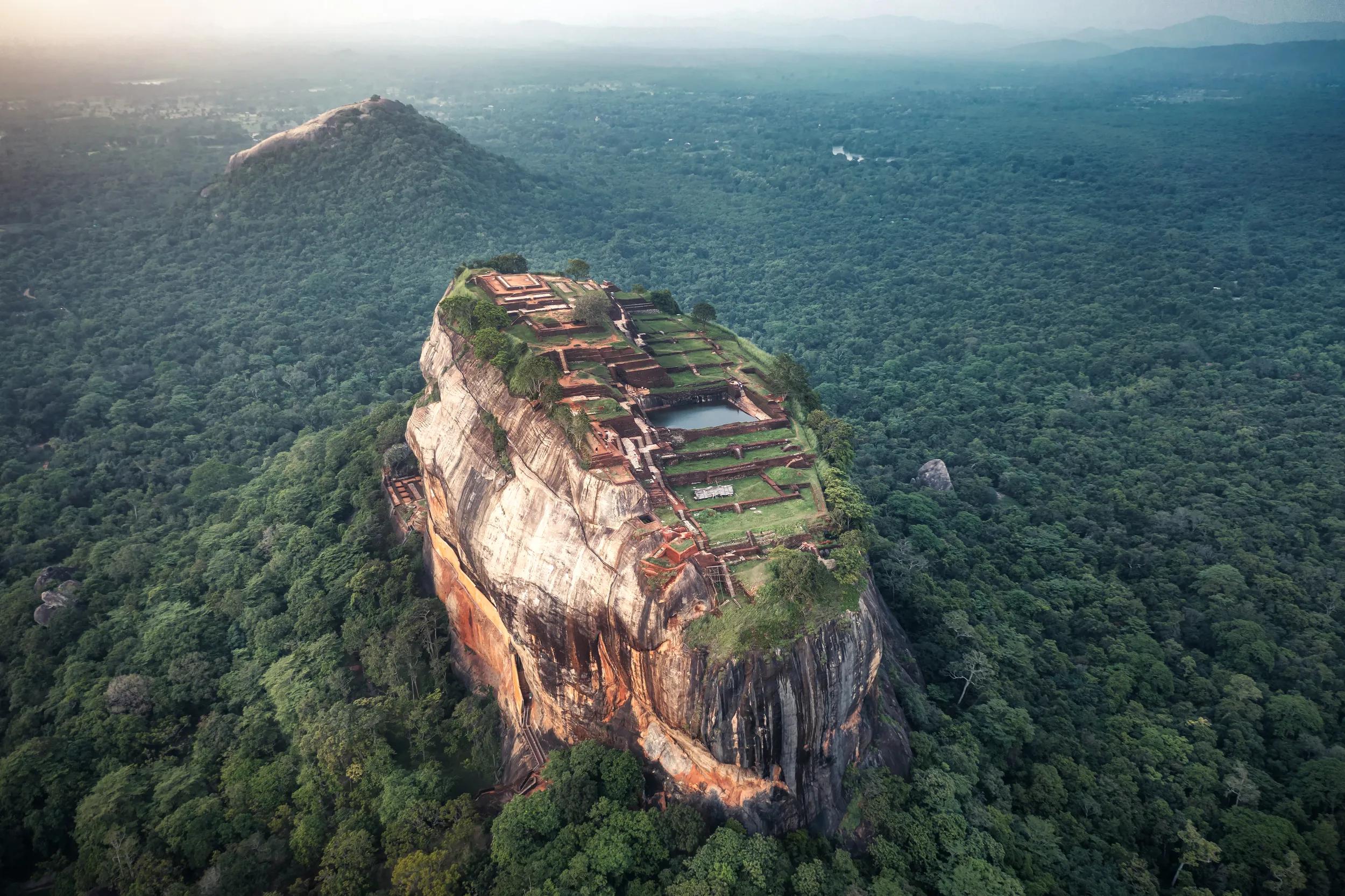 Drone photo of the magnificent sunset view of the Sigiriya Lion's Rock, in Sri Lanka...Sigiriya is an ancient rock fortress located in the northern Matale District near the town of Dambulla in the Central Province, Sri Lanka. ..It is a site of historical and archaeological significance that is dominated by a massive column of rock 180m high...Photo taken by drone device.