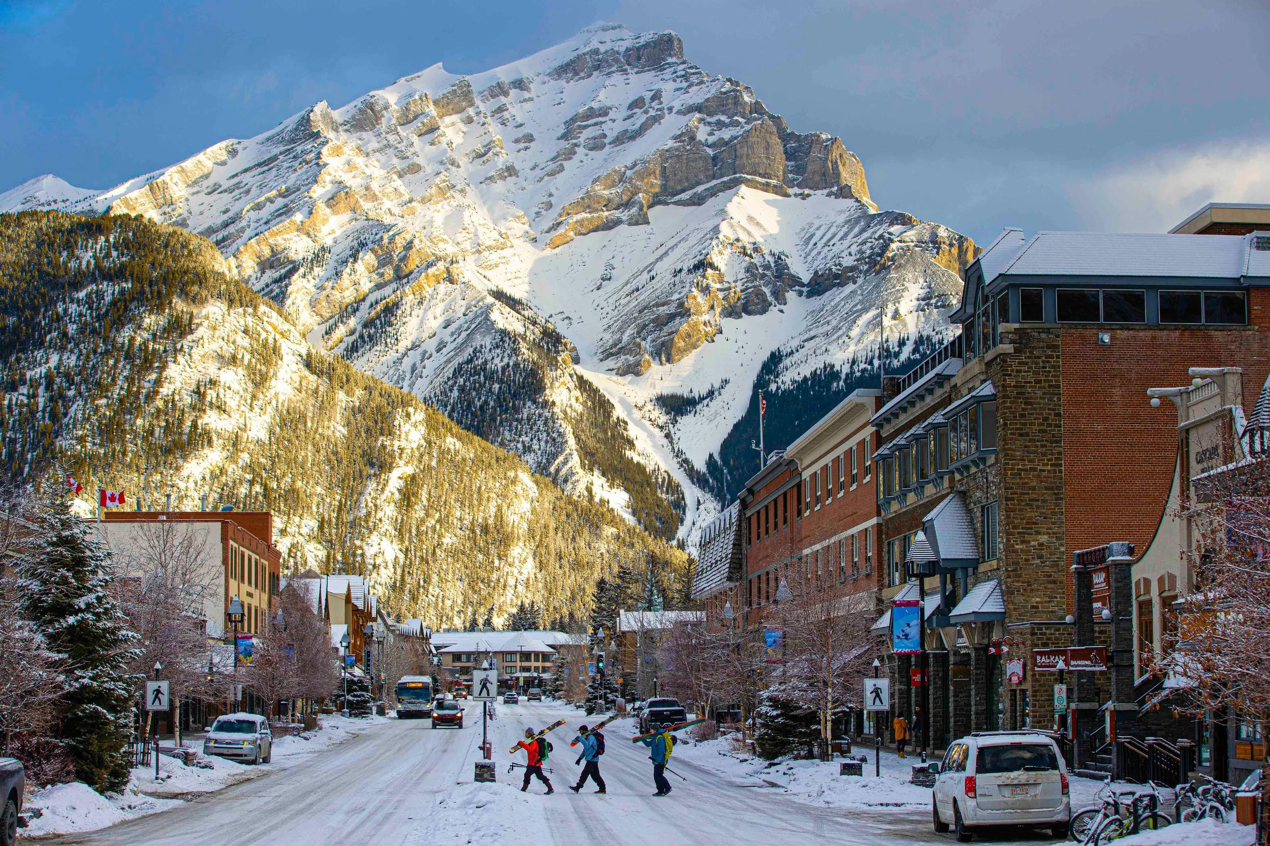 People with skiis crossing Banff Avenue in winter, Banff, Canada.