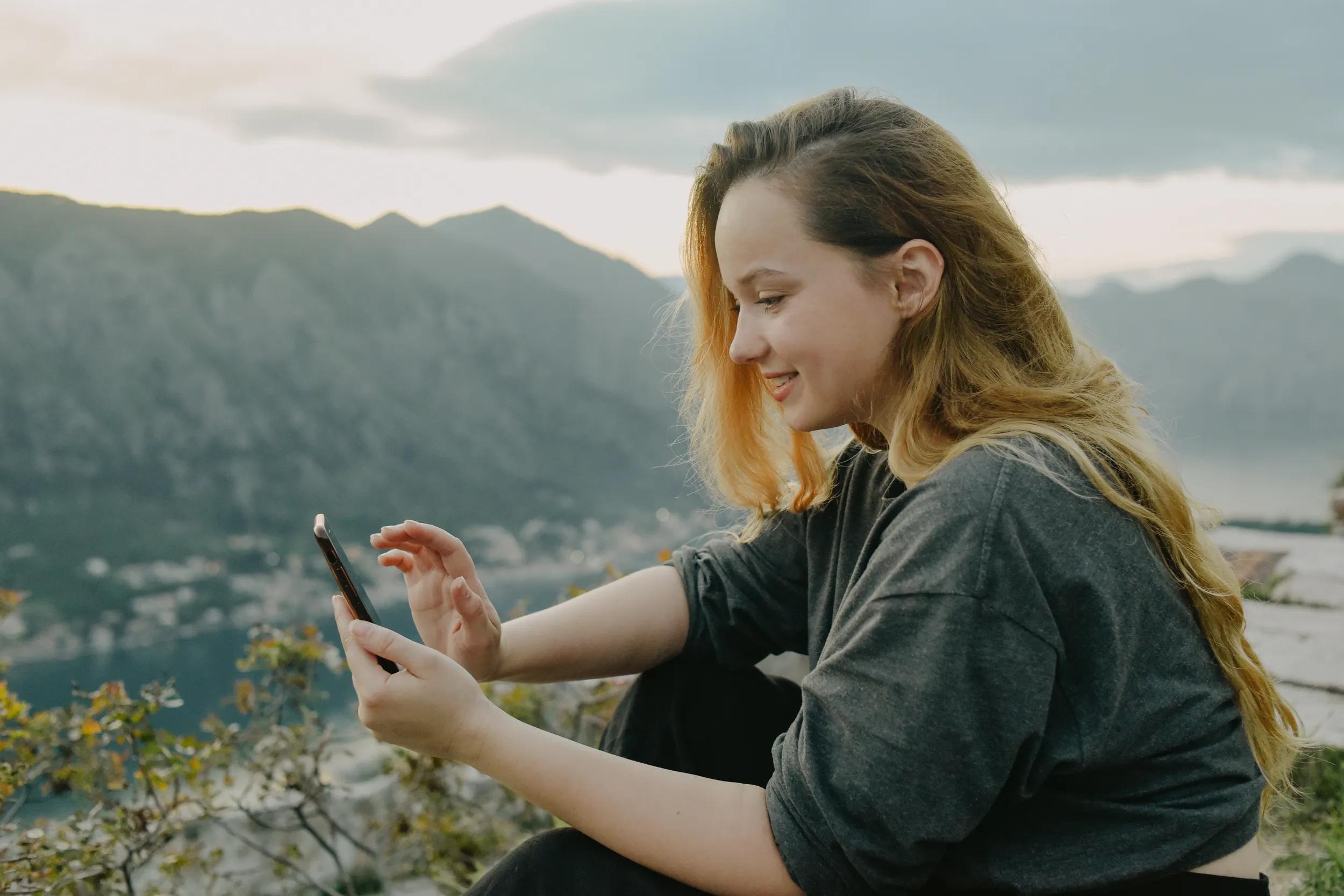 Woman on top of a mountain in Montenegro, Kotor. The girl looks at the smartphone, writes something, prints