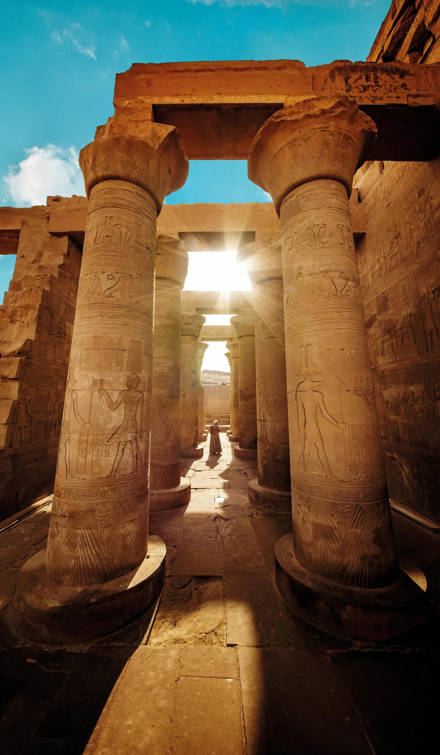 A person walking between carved stone columns in the ancient Egyptian Temple of Kom Ombo on the Nile River near Aswan and Luxor.