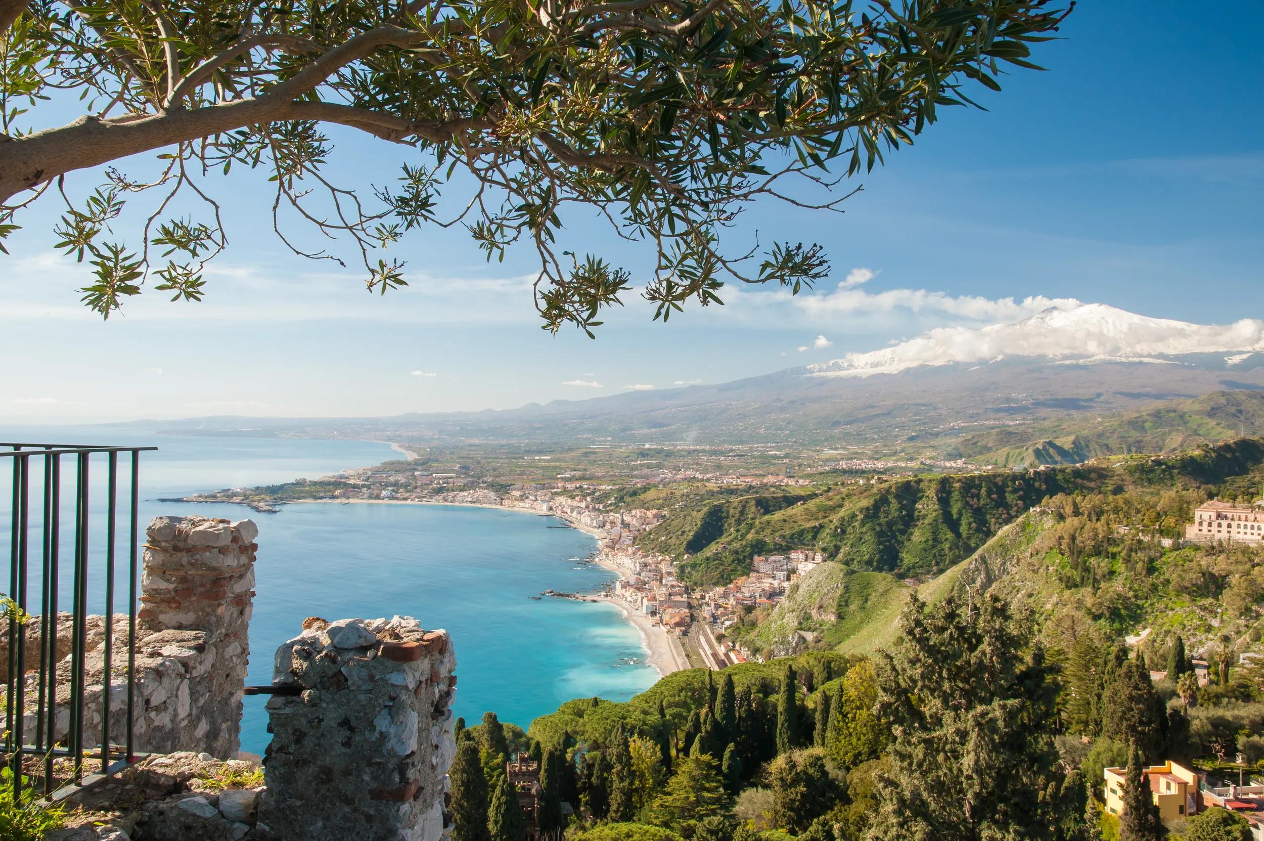 The touristic village Giardini Naxos, East Sicily, and snowy Mount Etna seen from the roman theater in Taormina.