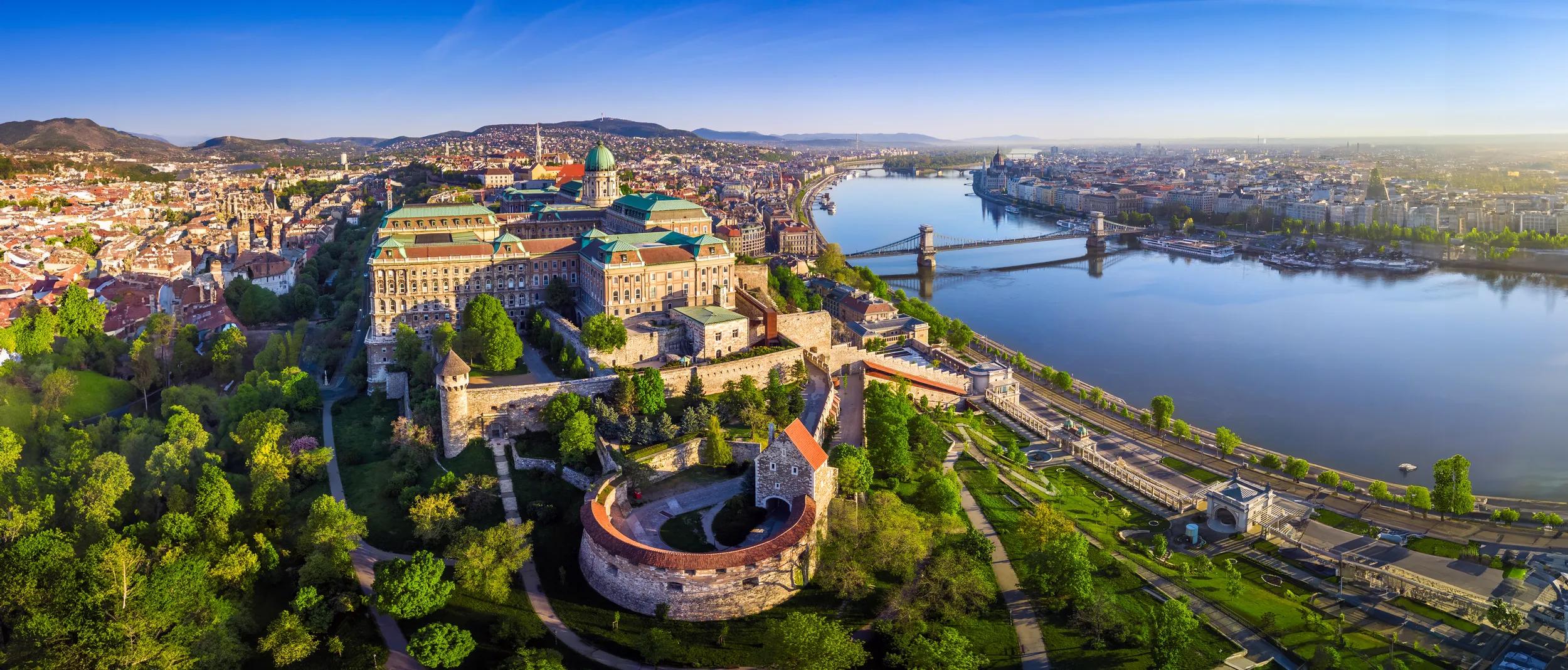 Budapest, Hungary - Aerial panoramic skyline view of Buda Castle Royal Palace with Szechenyi Chain Bridge, Hungarian Parliament and Matthias Church at sunrise with clear blue sky